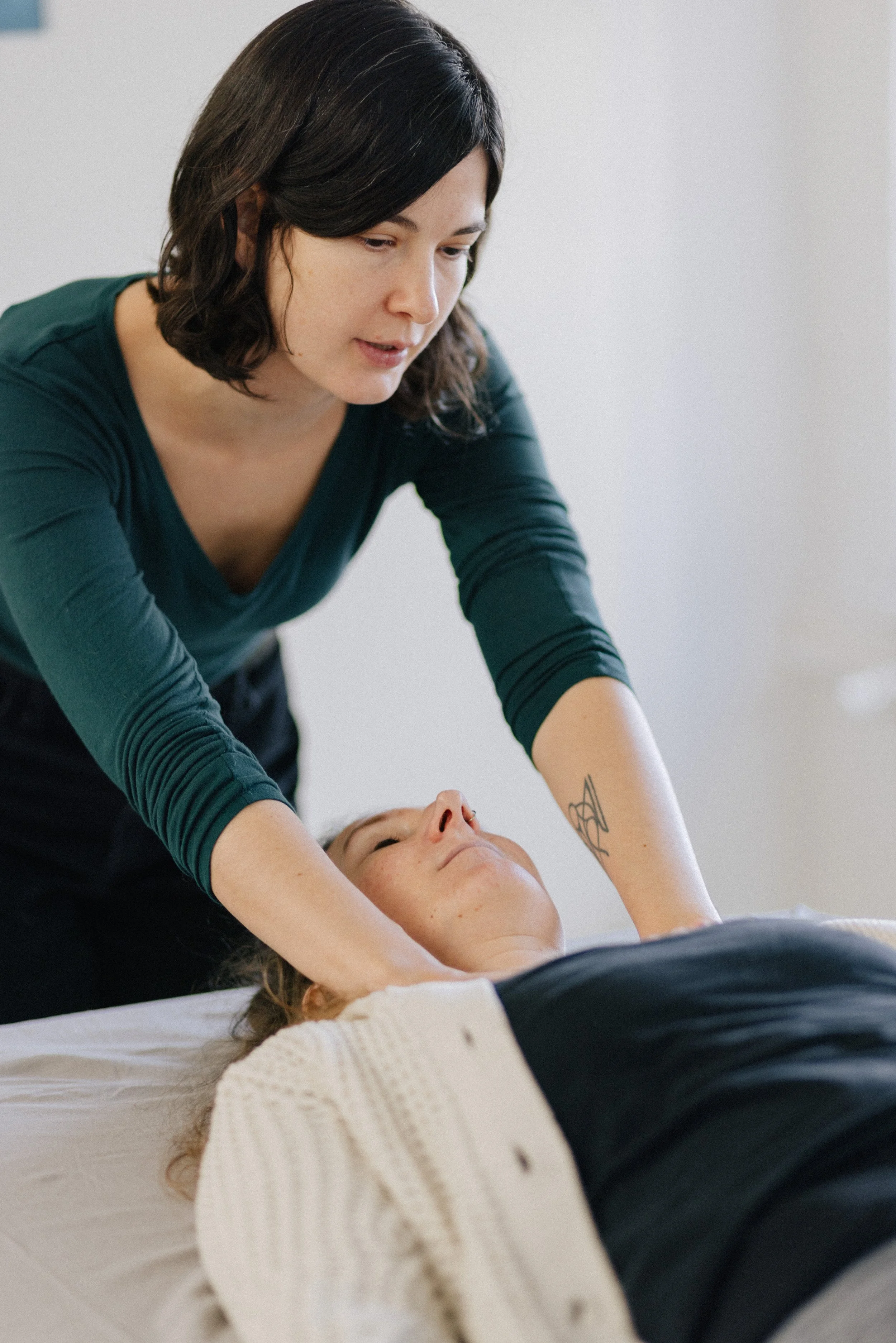 A woman giving a massage to a person lying on a bed.
