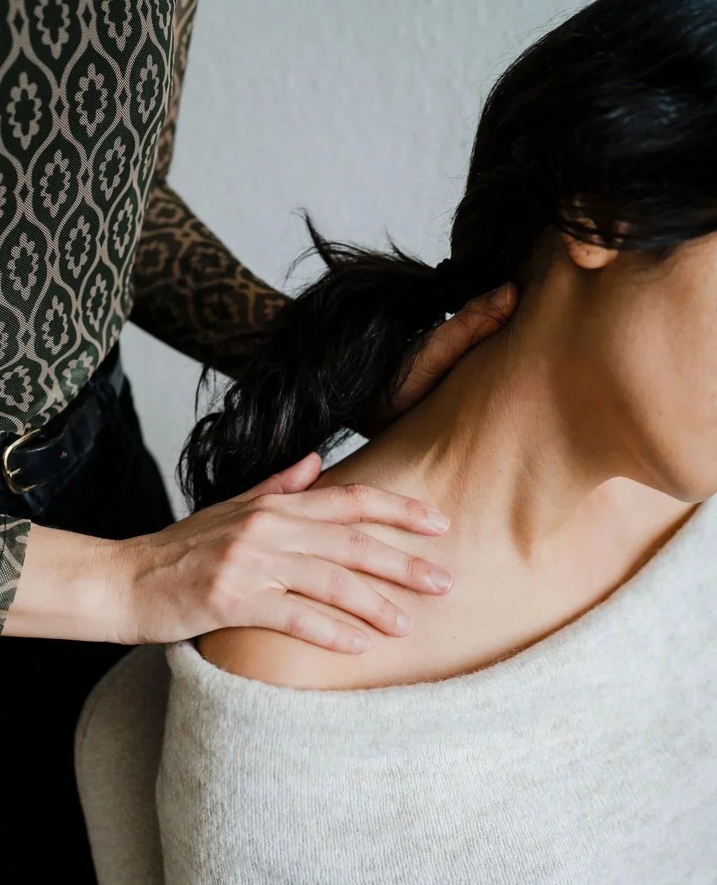 A person receiving a Pantarei Approach Bodywork session from a Pantarei Approach Practitioner with a patterned sleeve.