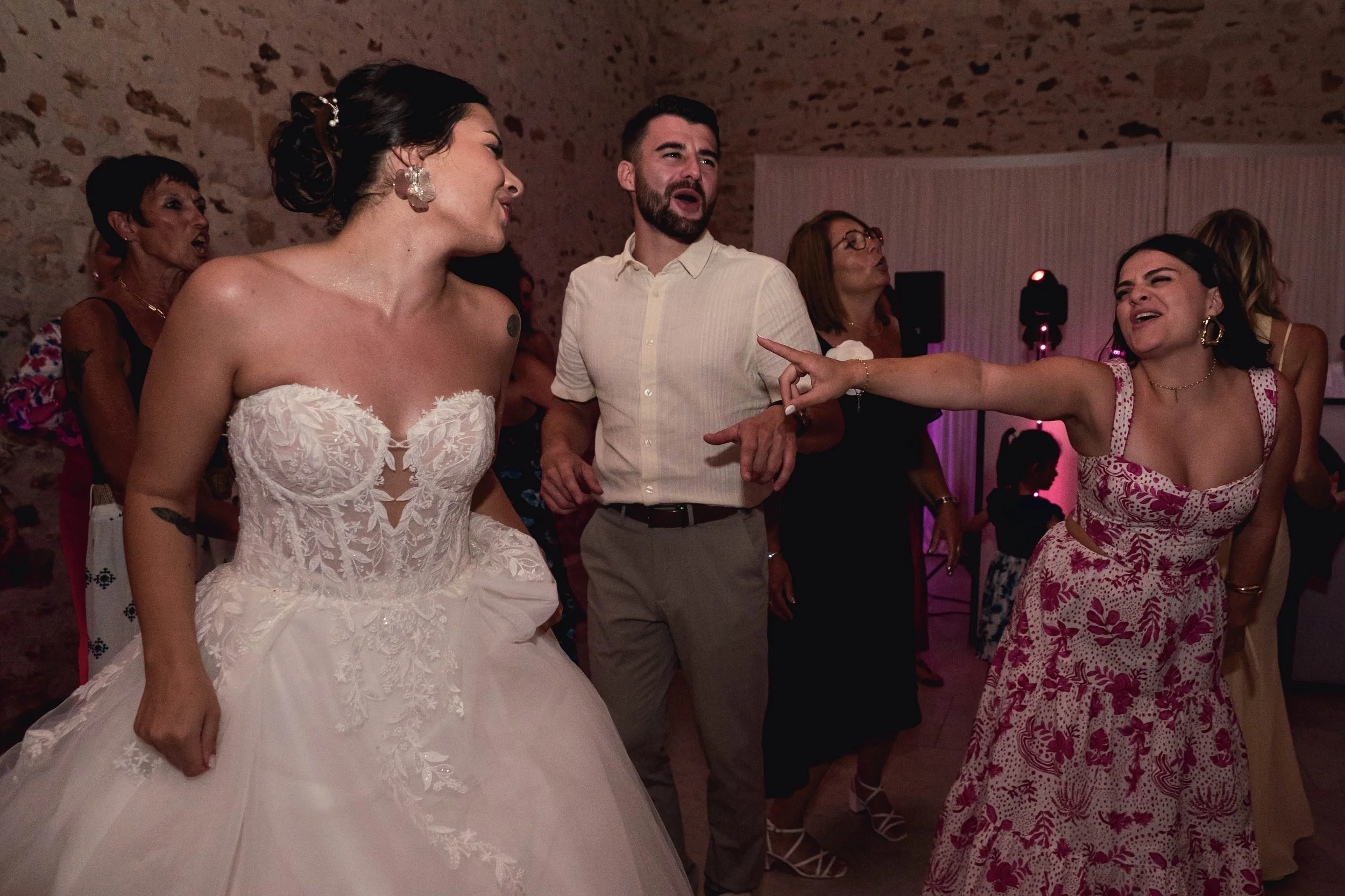 Groupe de personnes dansant lors d'une fête, avec une femme en robe de mariée en premier plan