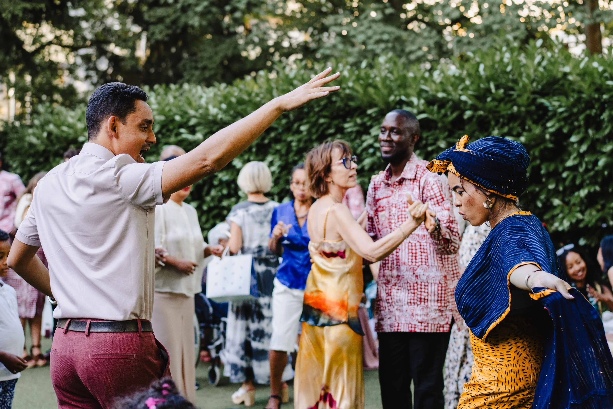 Groupe de personnes qui dansent lors d'une fête en extérieur, avec des arbres en arrière-plan.