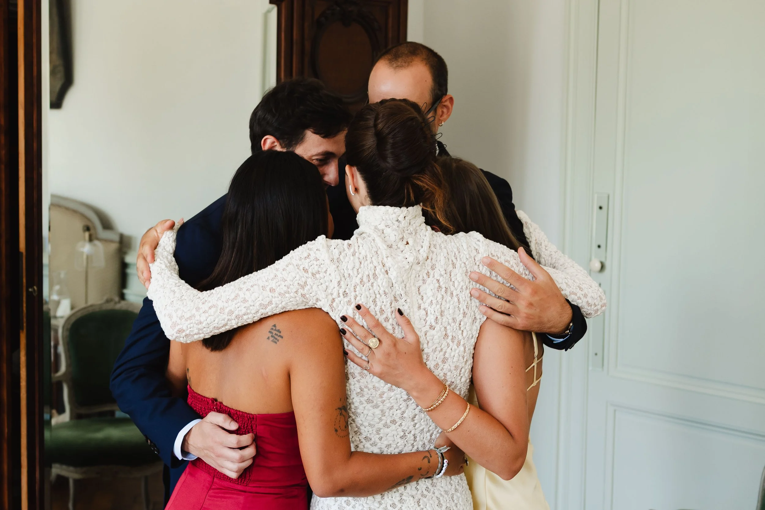 Un groupe de personnes fait un câlin collectif dans une pièce intérieure, exprimant une émotion d'affection ou de célébration.