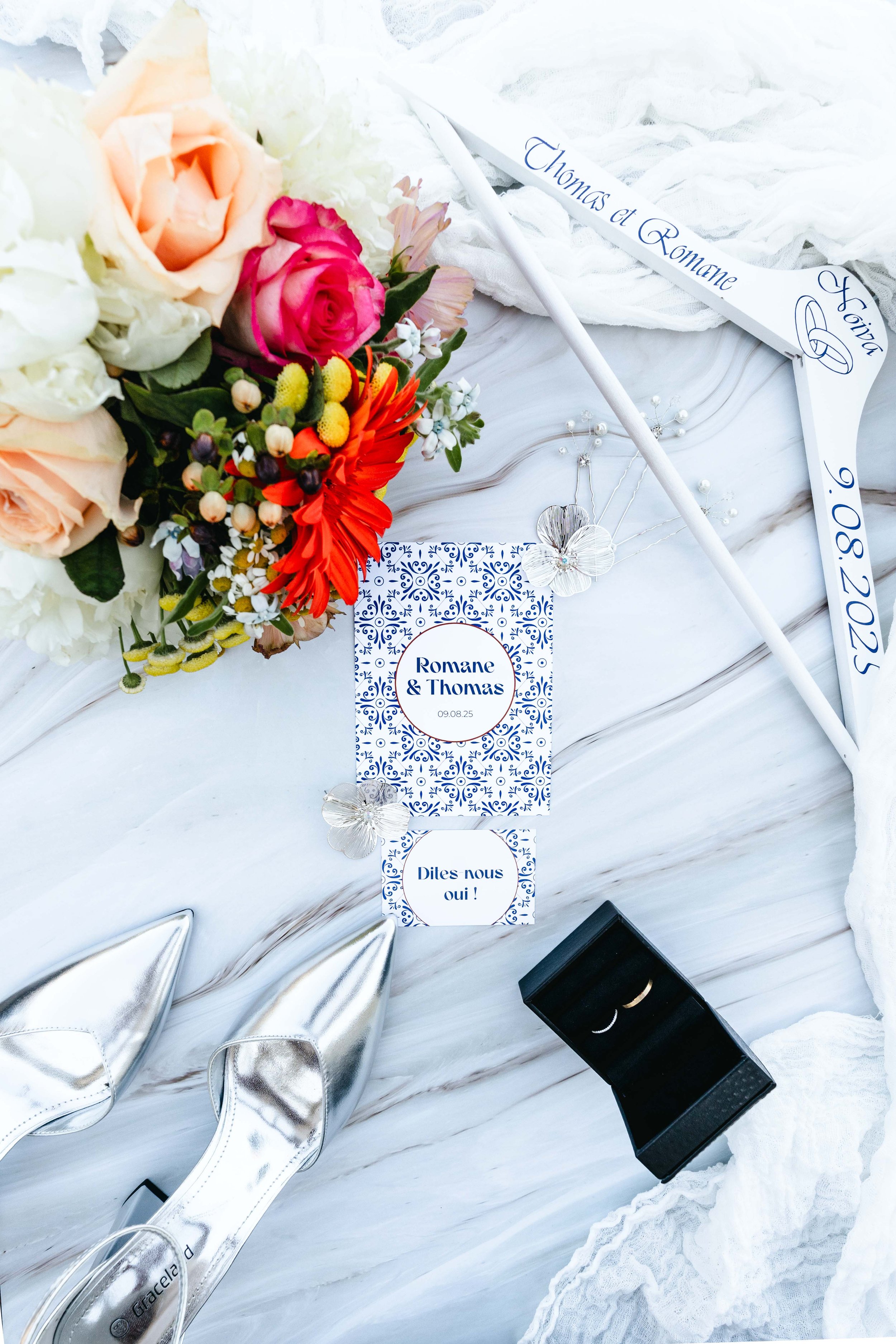 Accessoire de mariage avec bouquet de fleurs, tickets, alliances, et décoration sur un plan blanc et blanc.