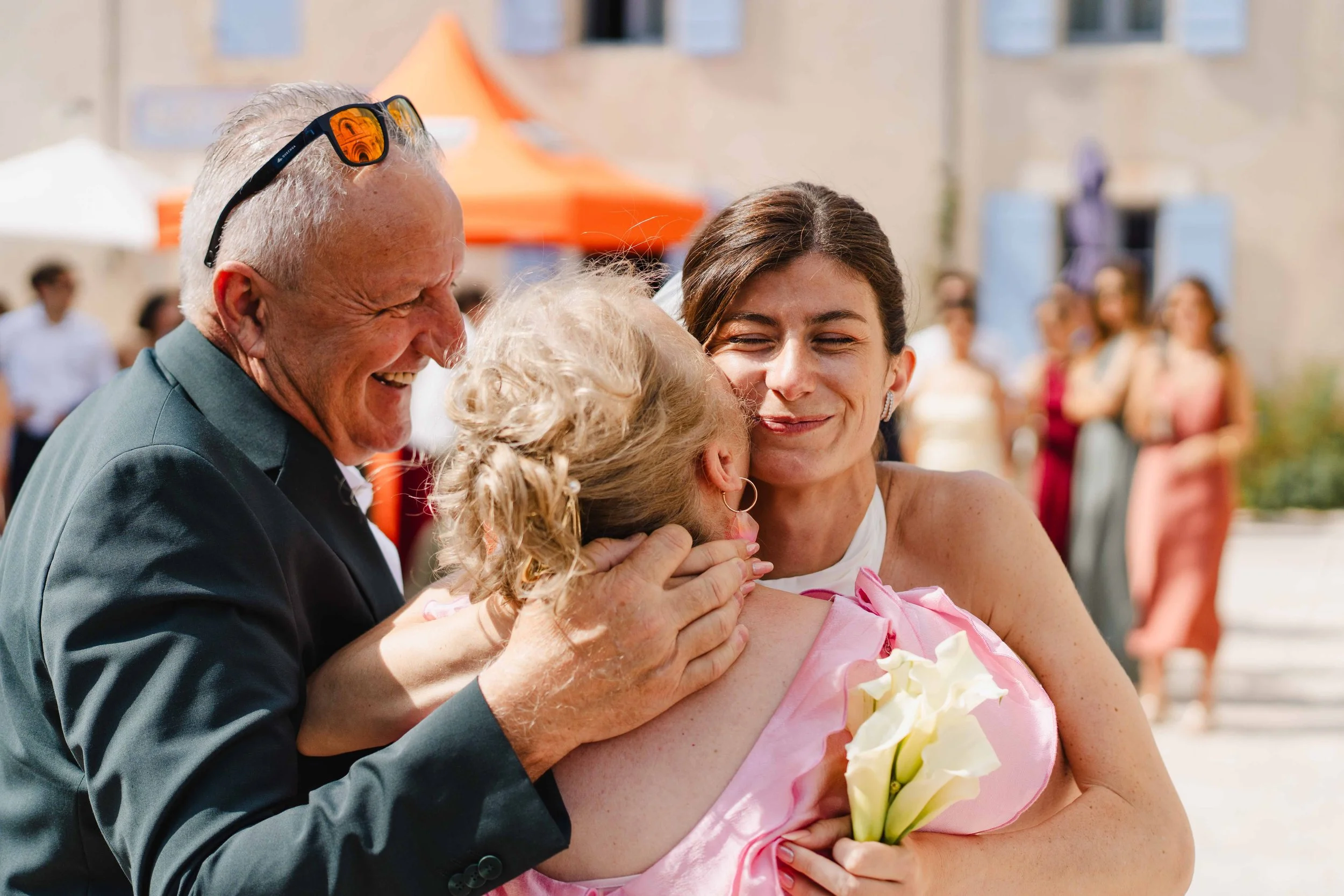 Une famille en costume souriante lors d'une fête en extérieur, entourée de plusieurs personnes