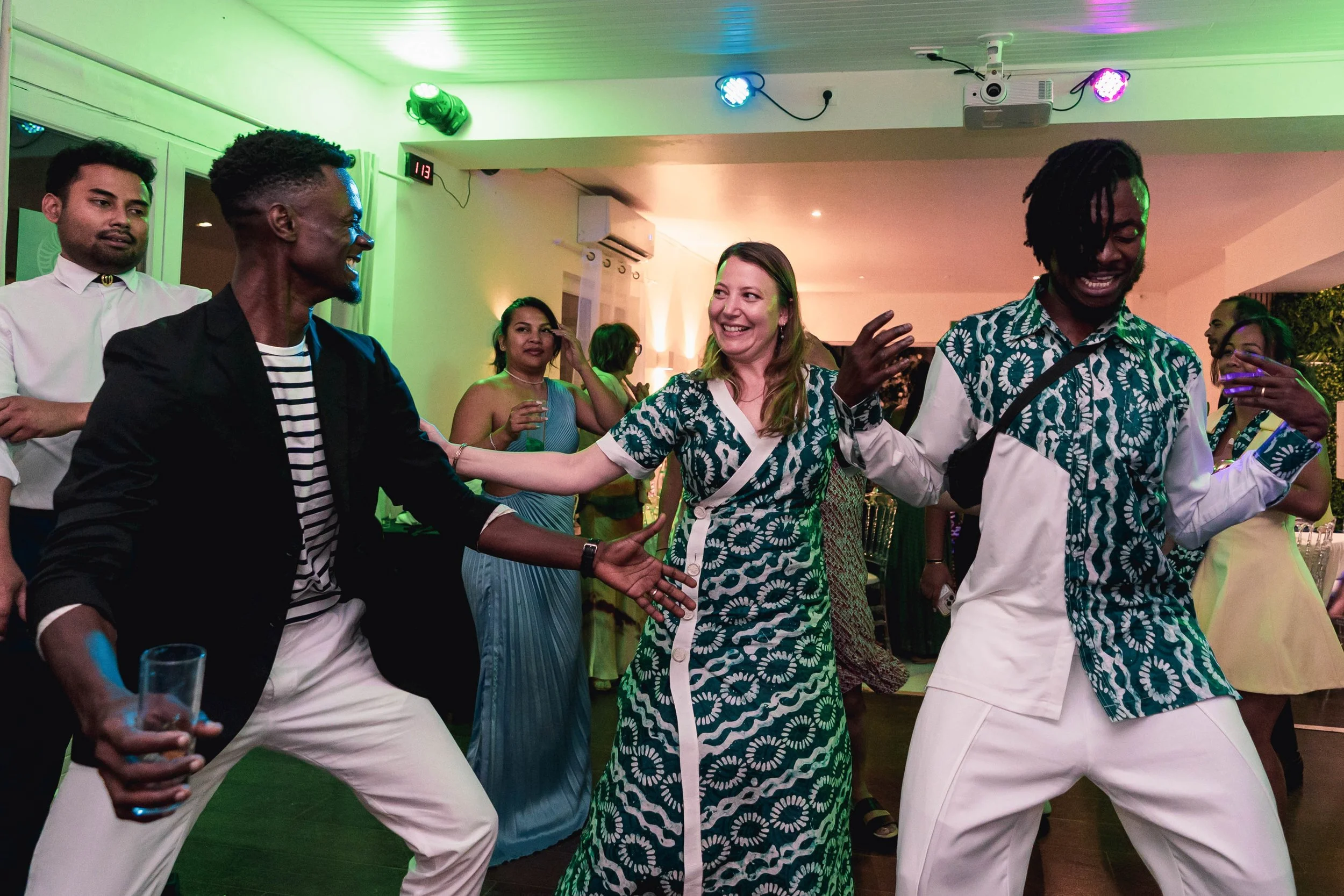 Groupe de personnes dansant lors d'une fête ou d'un événement social, avec des éclairages colorés.