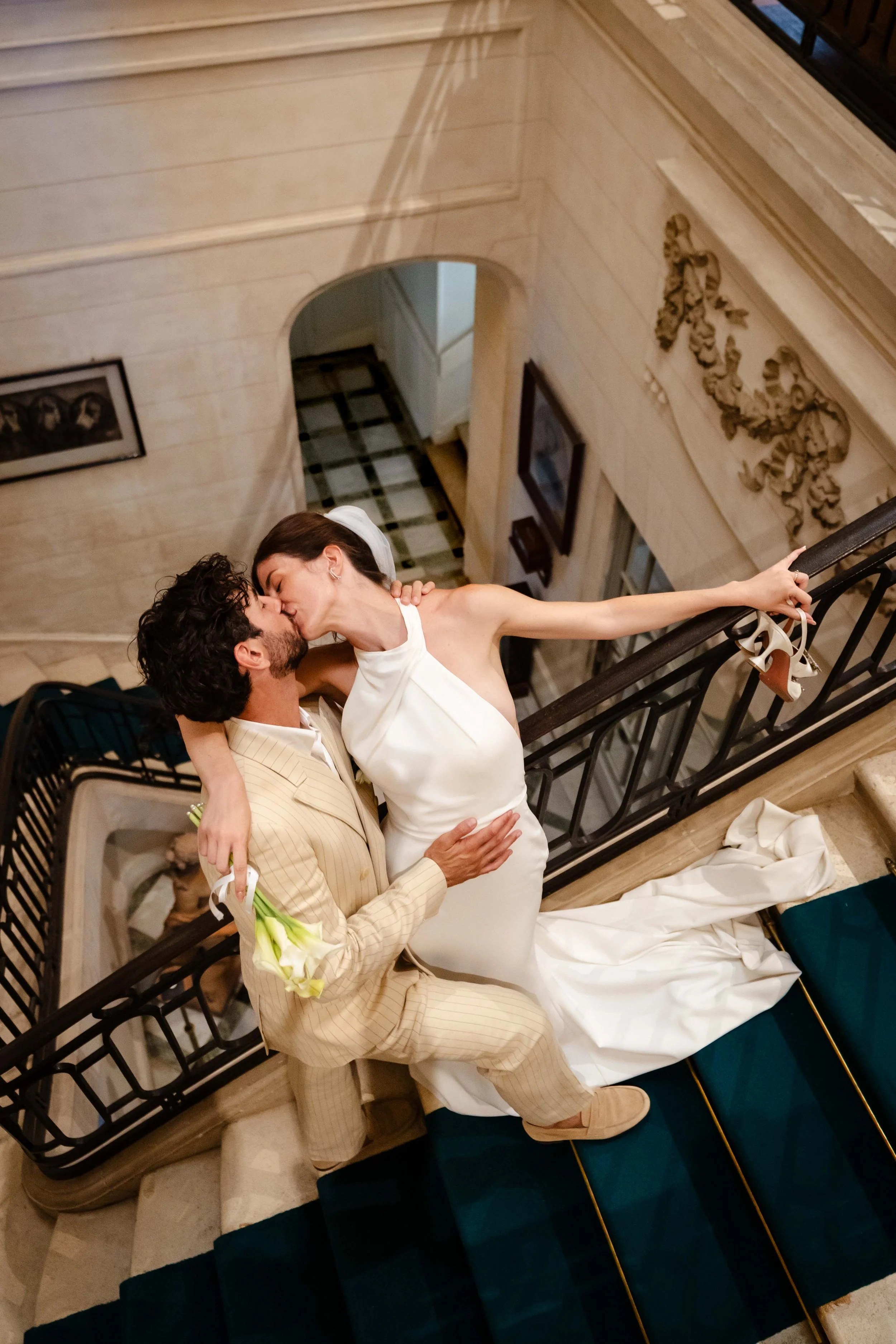 Un couple en robe de mariage s'embrassant sur un escalier en intérieur.