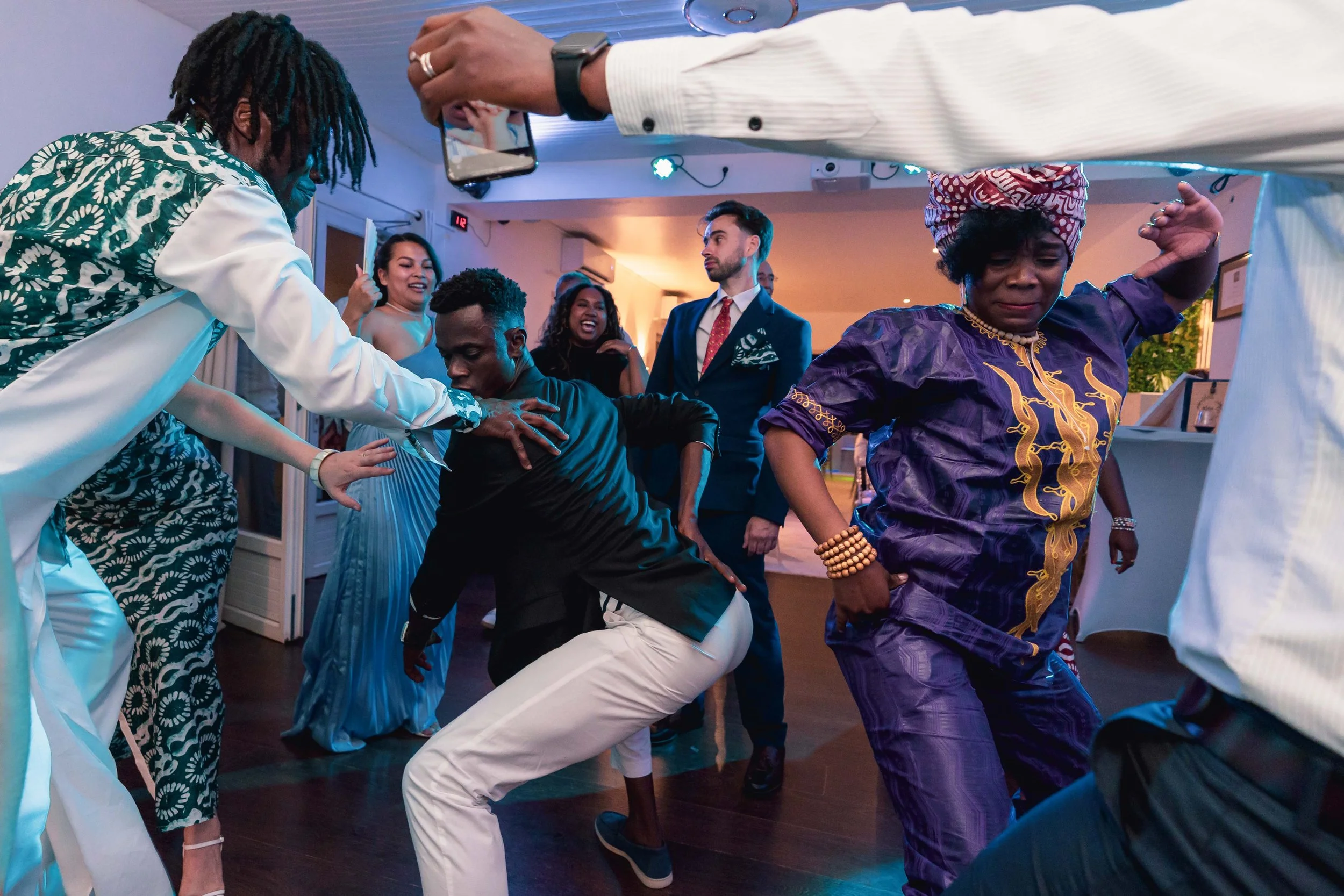 Groupe de personnes dansant et s'amusant lors d'une fête ou d'un événement, certain(e)s en vêtements traditionnels africains, ambiance joyeuse et dynamique.