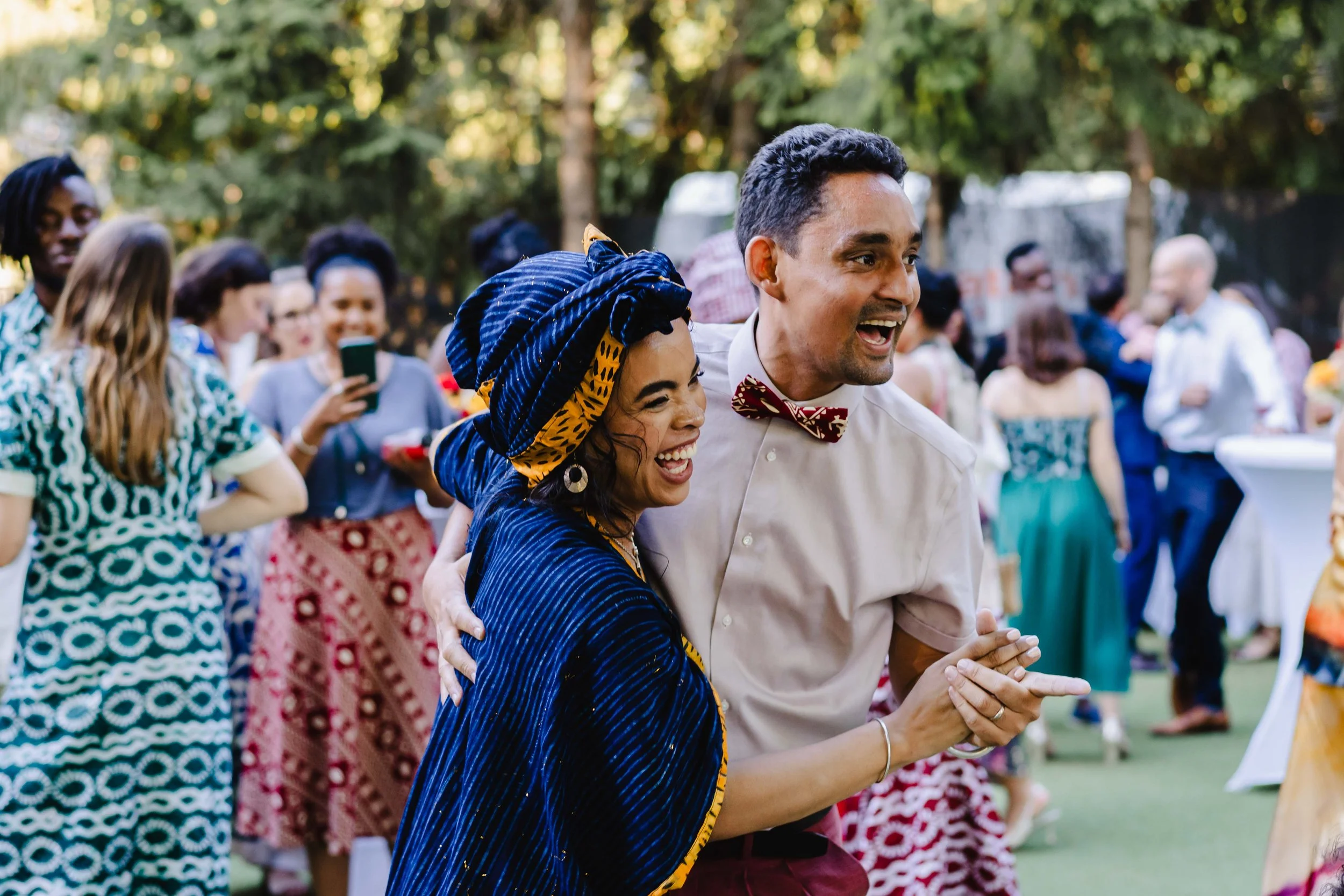 Un groupe de personnes dansant et s'amusant lors d'une fête en extérieur, avec deux personnes au premier plan, un homme et une femme, qui sourient et semblent partager un moment joyeux.