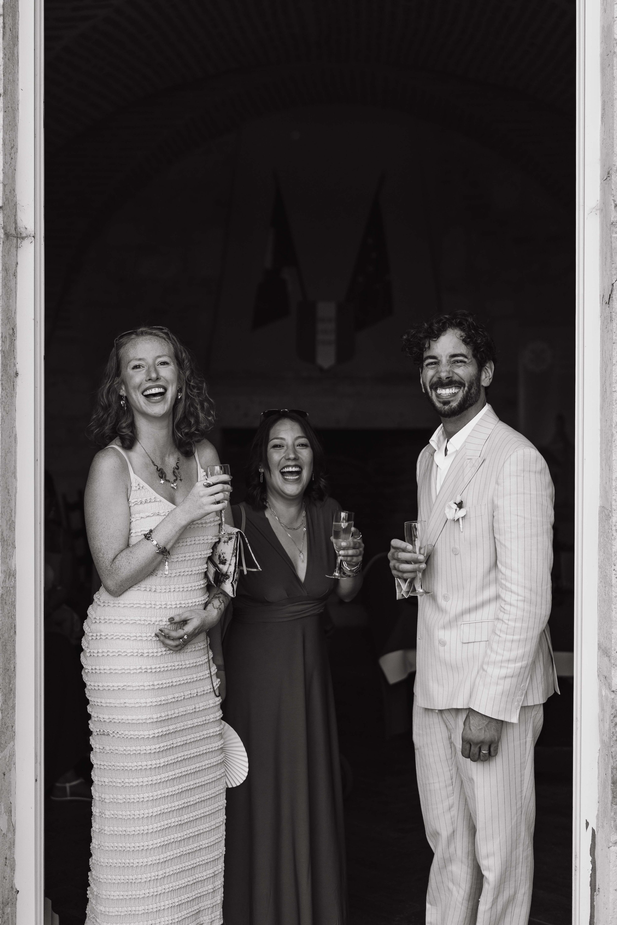 Trois personnes souriantes lors d'une célébration, tenant des verres de champagne, dans un espace intérieur avec un décor festif.