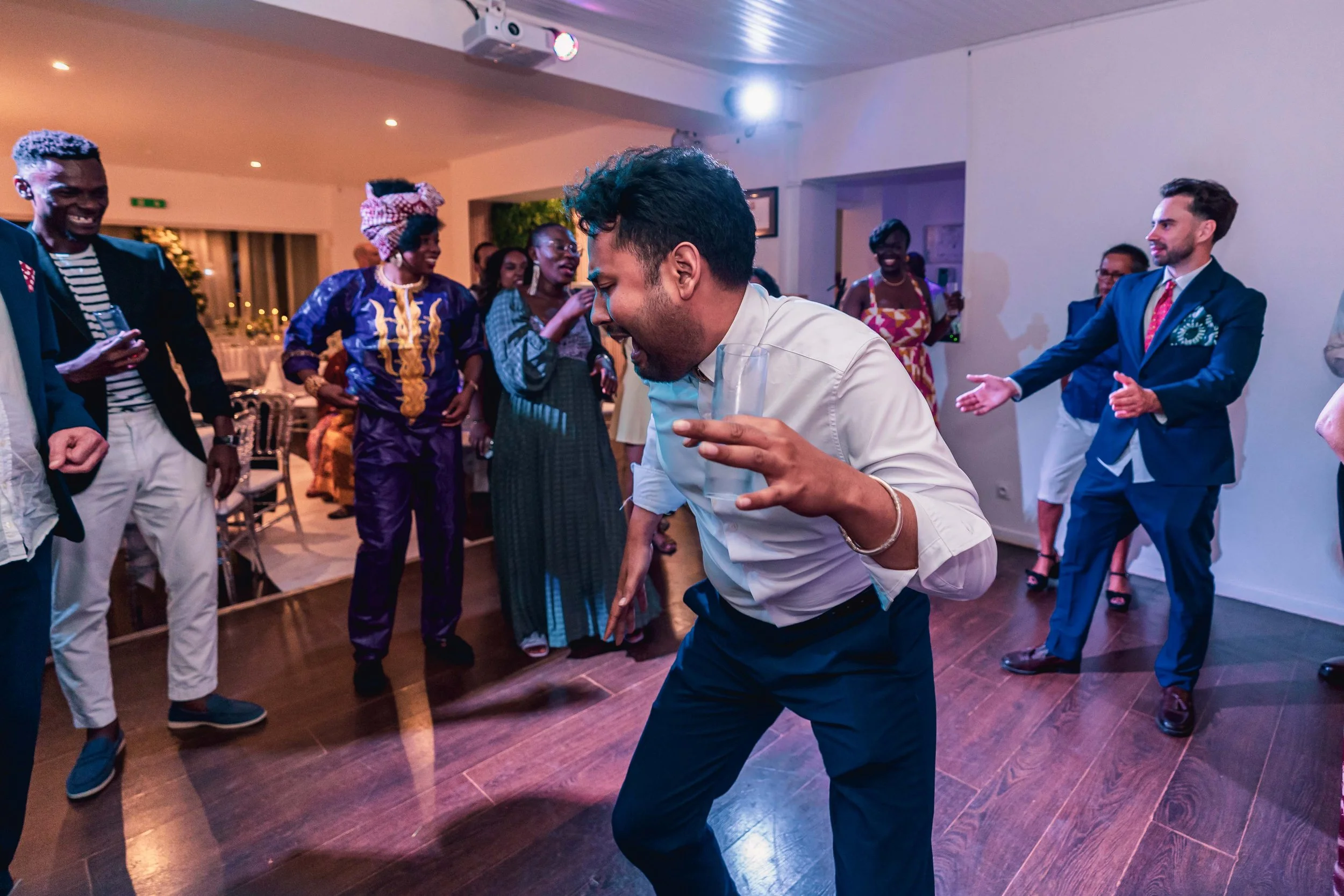 Groupe de personnes dansant et souriant lors d'une fête ou d'un événement social dans une salle intérieure.