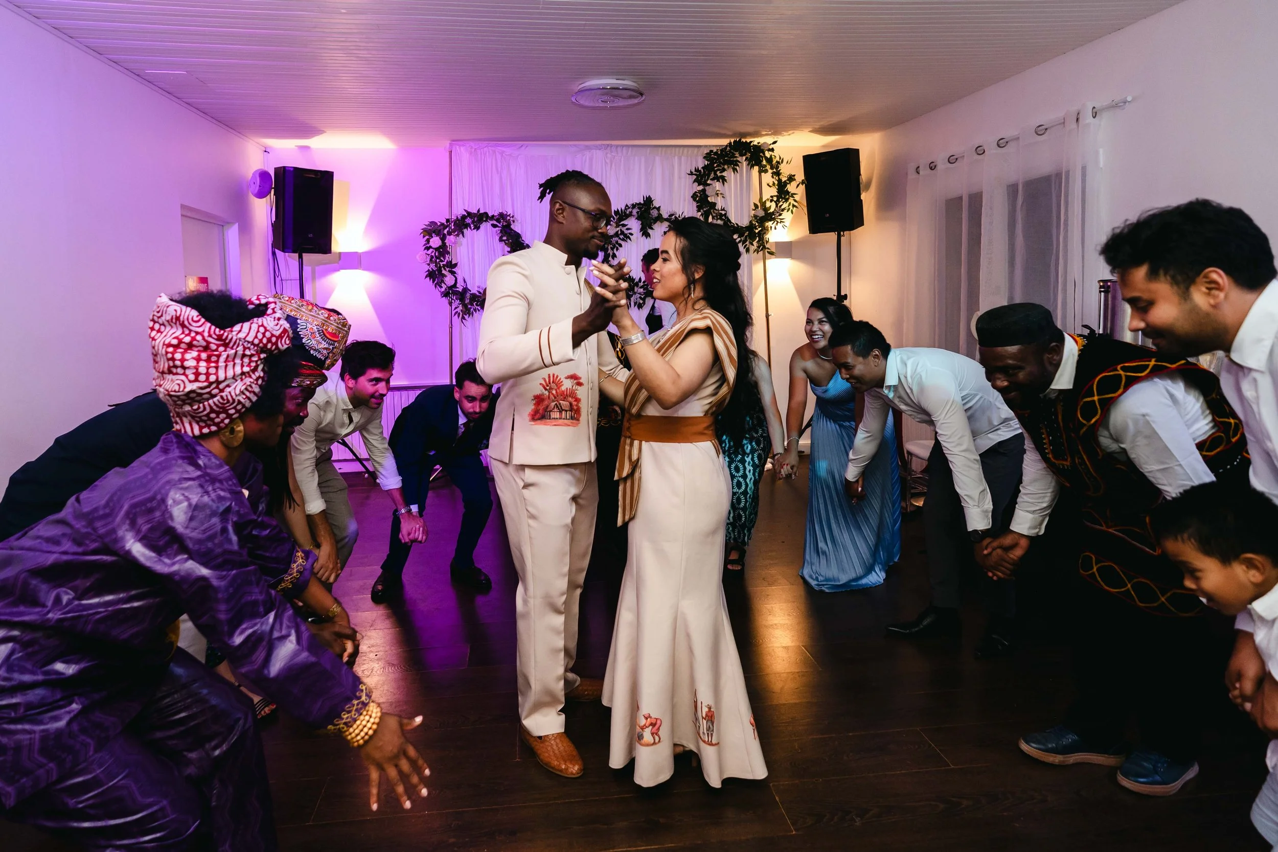 Un groupe de personnes dansant lors d'une fête, avec deux personnes au centre qui semblent danser le tango ou une danse similaire, entourées d'autres invités en costumes traditionnels et modernes dans la salle de réception du Moulin vert à Champigny