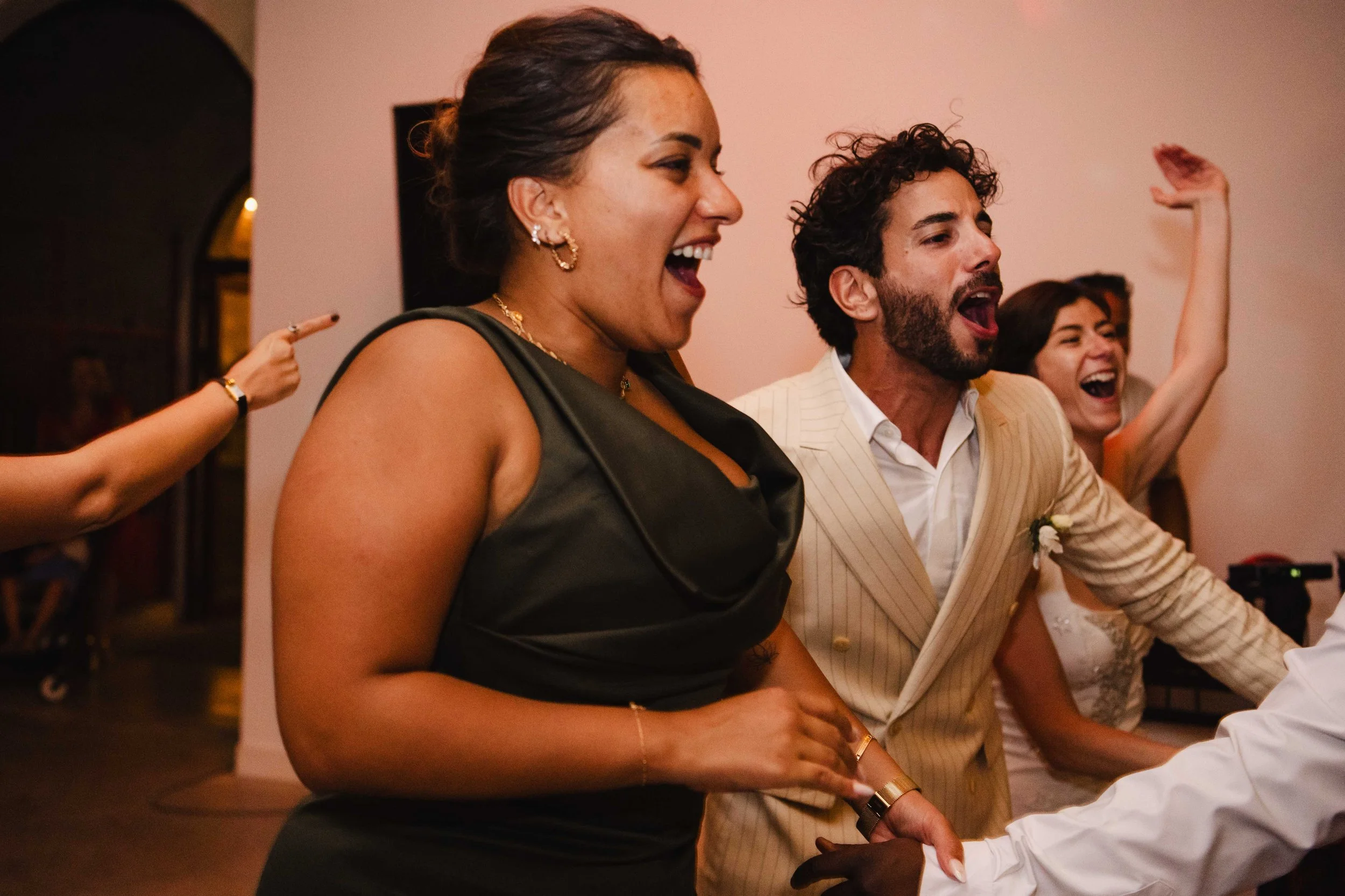 Groupe de personnes souriantes et joyeuses dans une fête ou un mariage, certaines dansent et s'amusent en groupe.