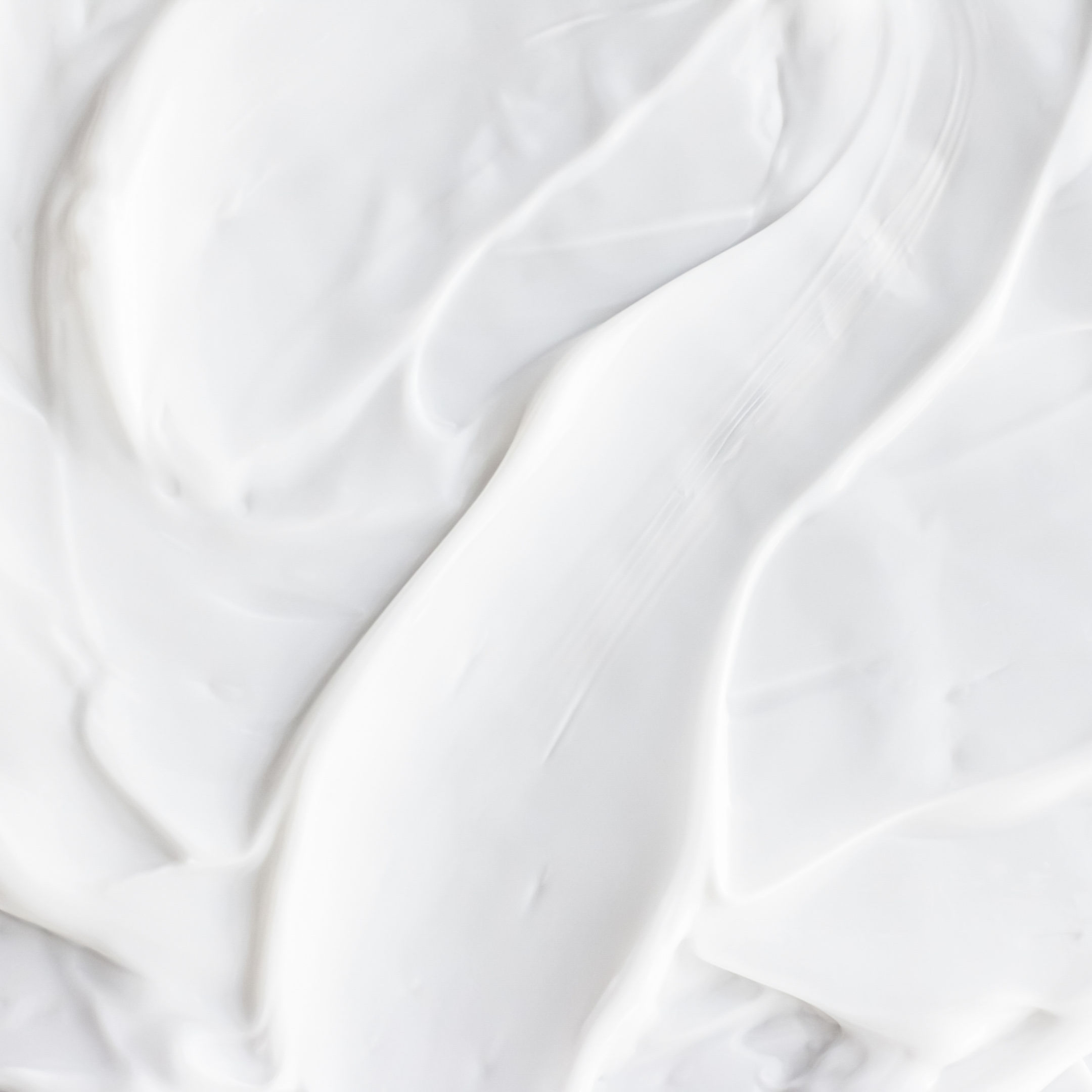 Close-up of smooth, creamy white substance, possibly whipped cream or lotion.