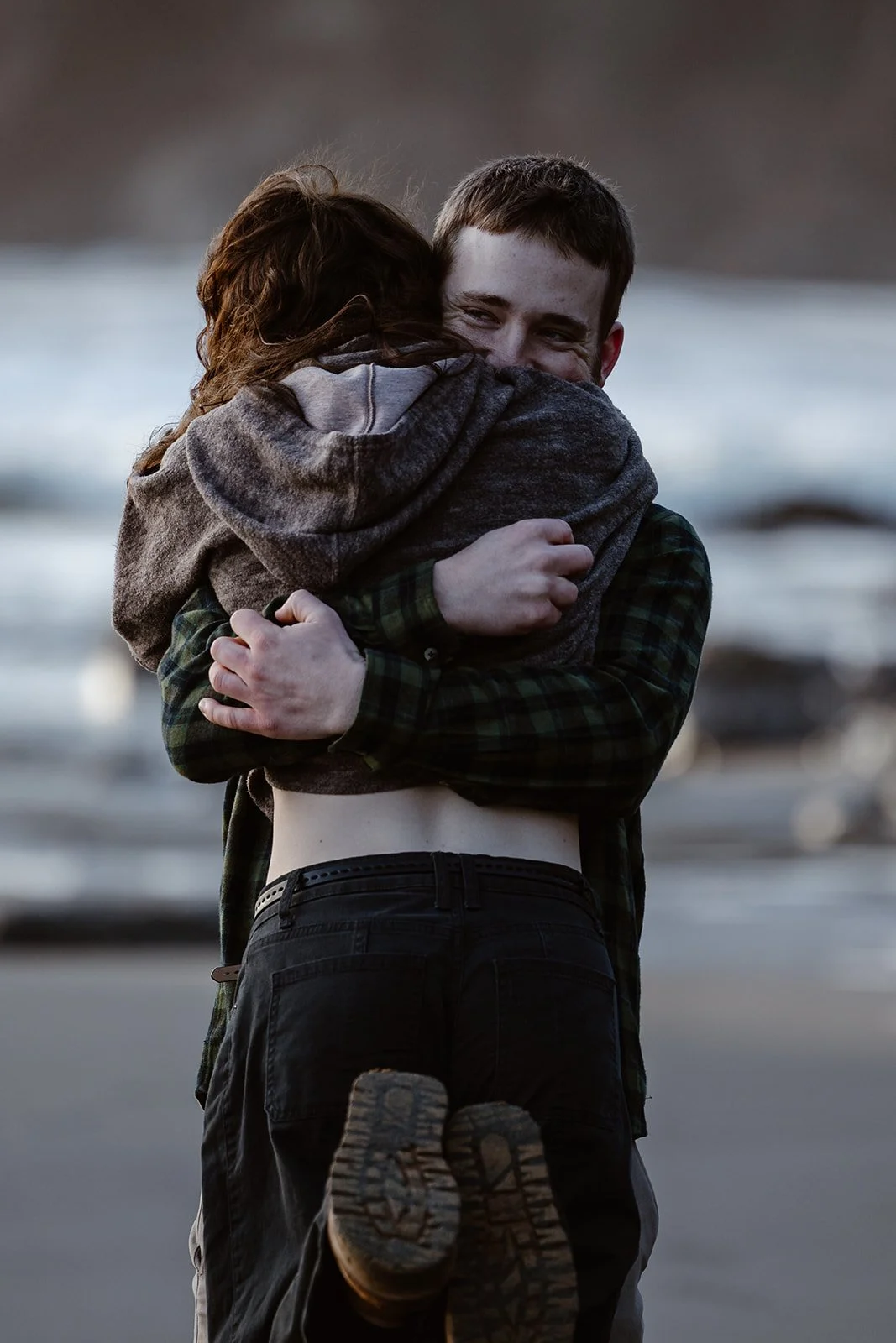 couple hugging after surprise engagement on the washington coast