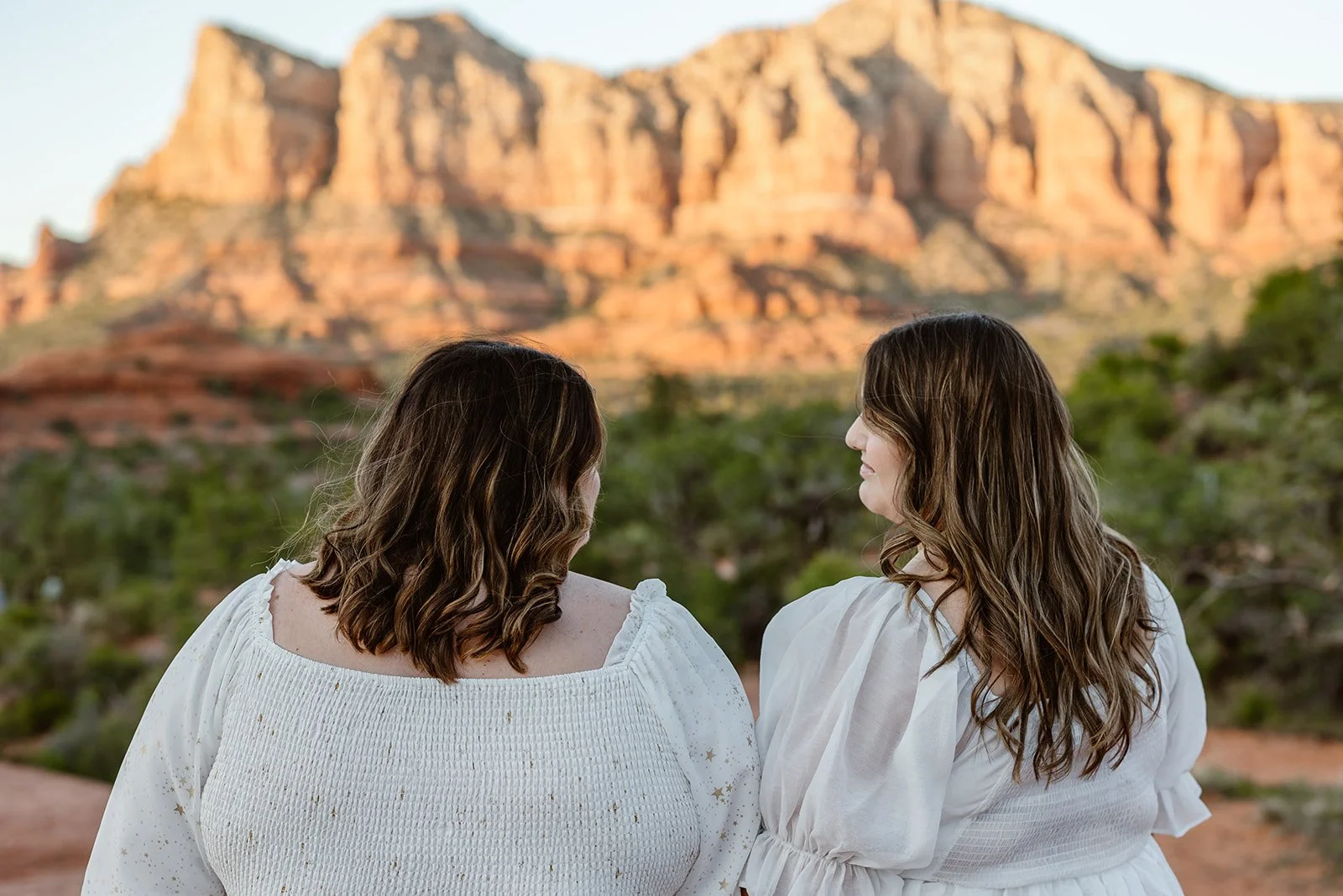 Two brides smiling at each other at courthouse butte for their elopement in Arizona