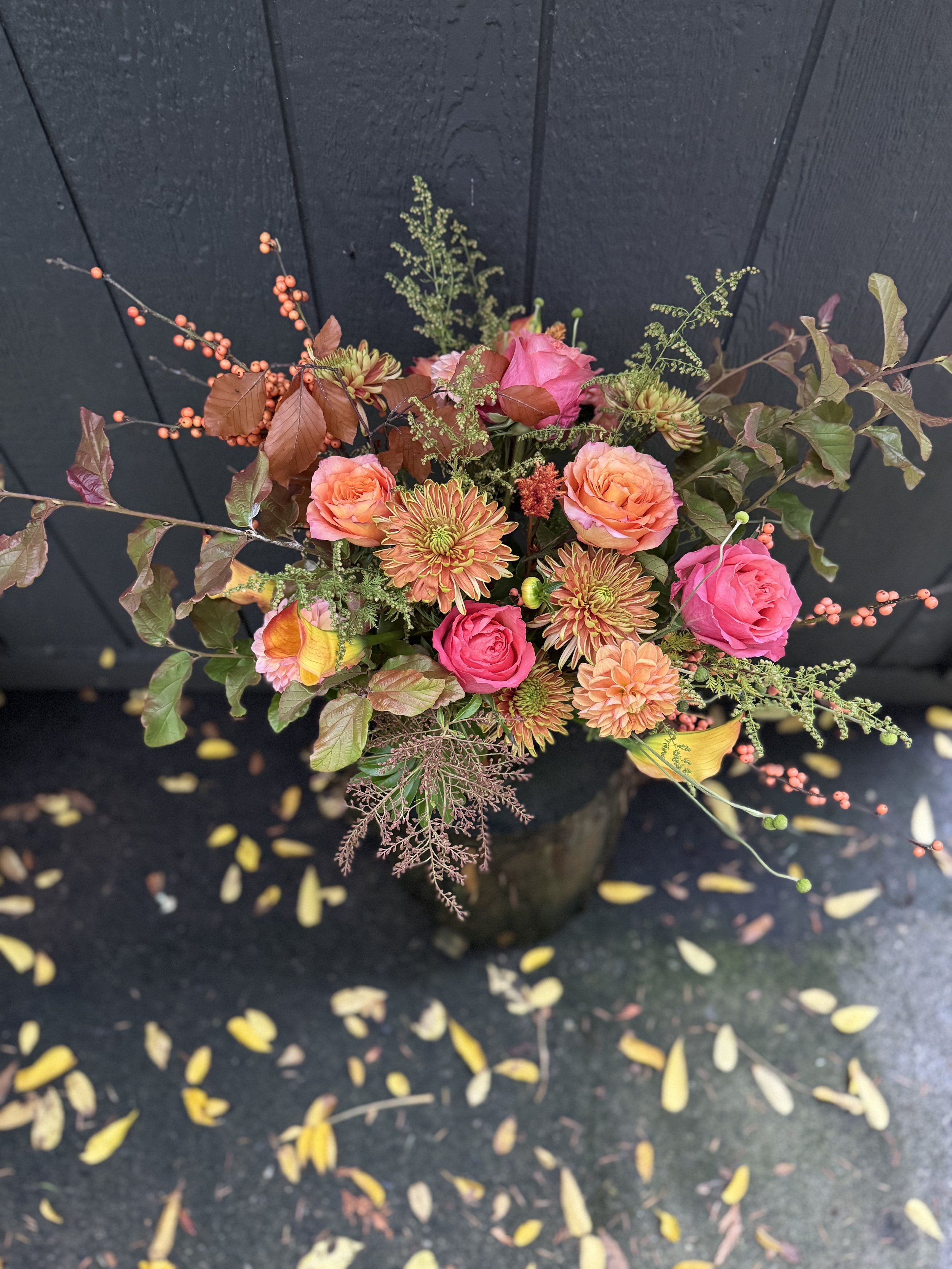 A close-up of a colorful bouquet of flowers including purple roses, white dahlias, anemones, baby's breath, and other assorted purple, white, and green flowers.