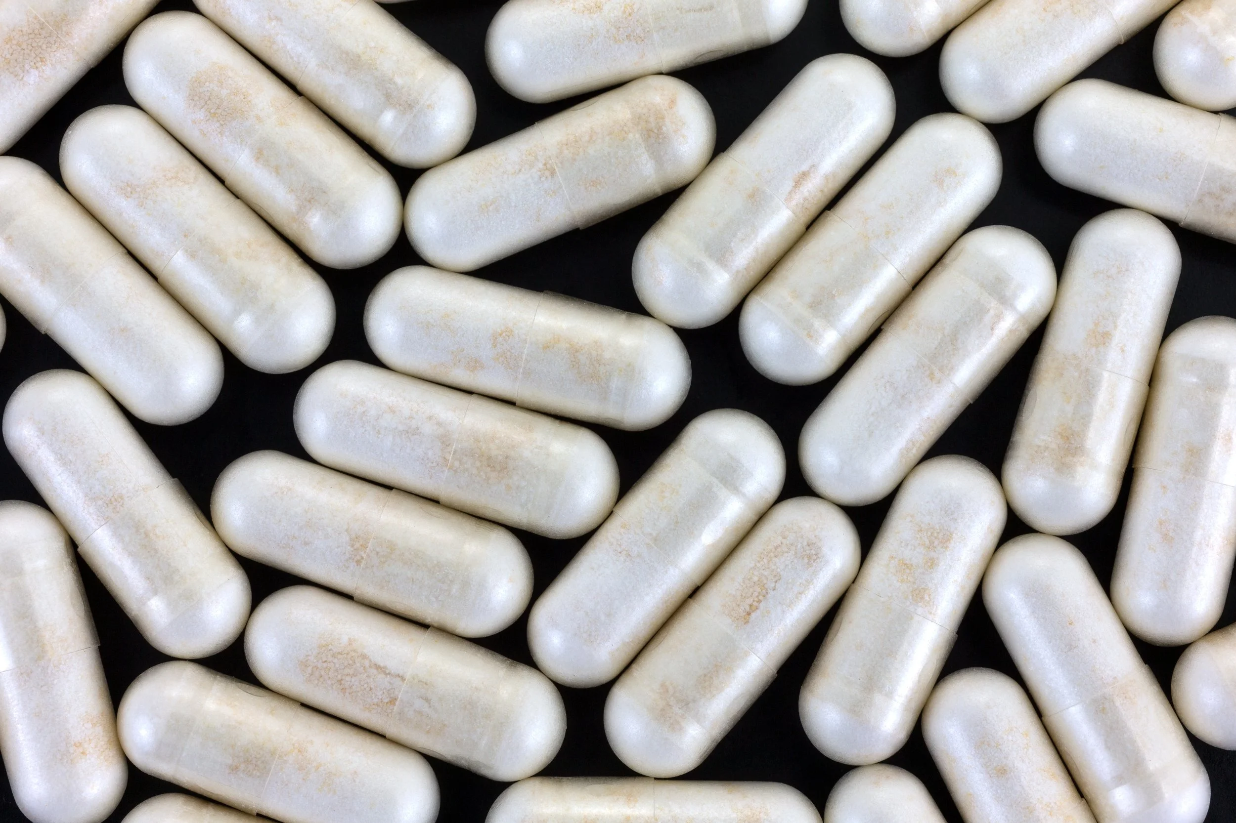 Nicotinamide riboside capsules arranged on a black background, commonly used as NAD+ dietary supplements.
