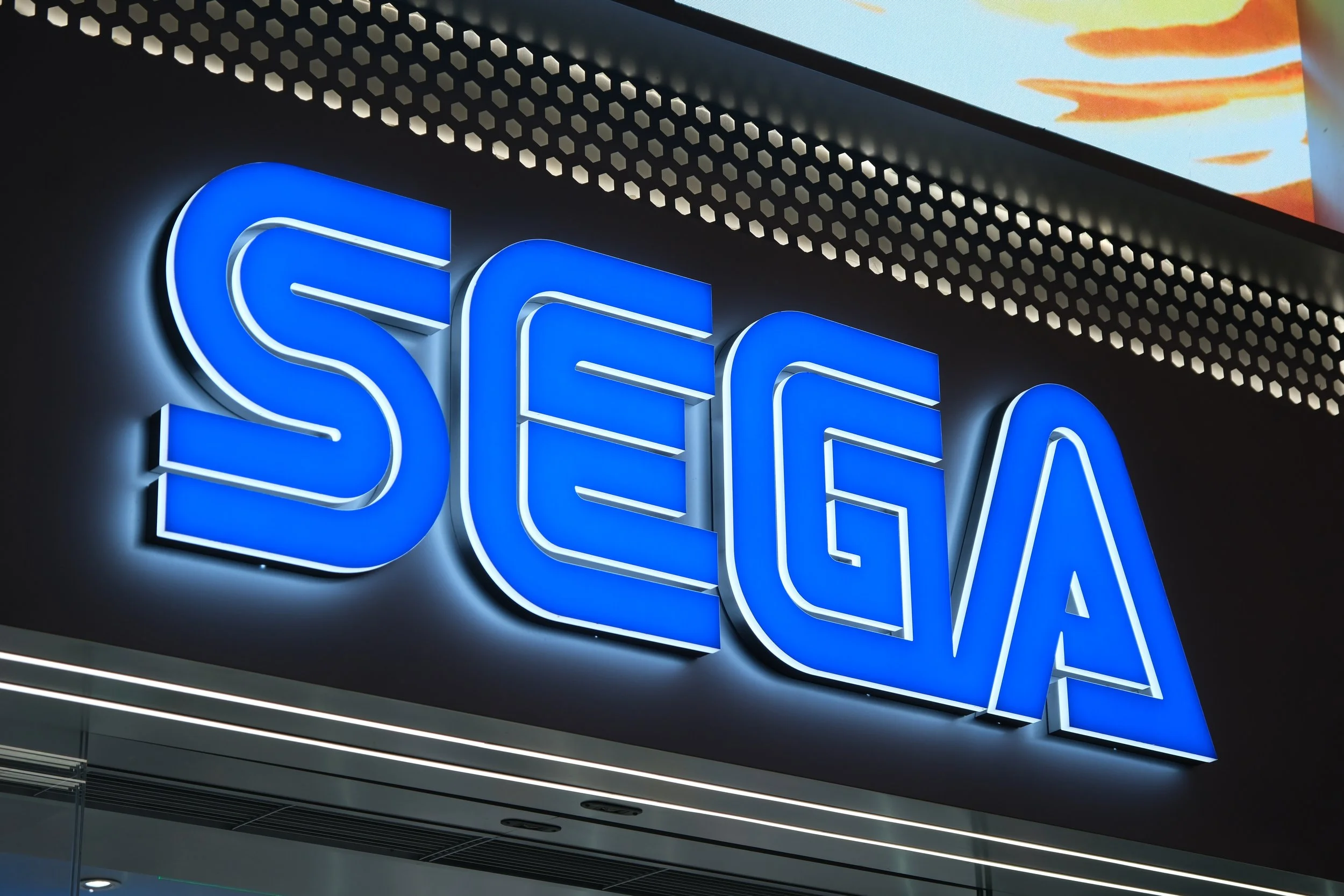 Illuminated SEGA logo signage on a modern storefront exterior, representing the global video game publisher and entertainment brand.