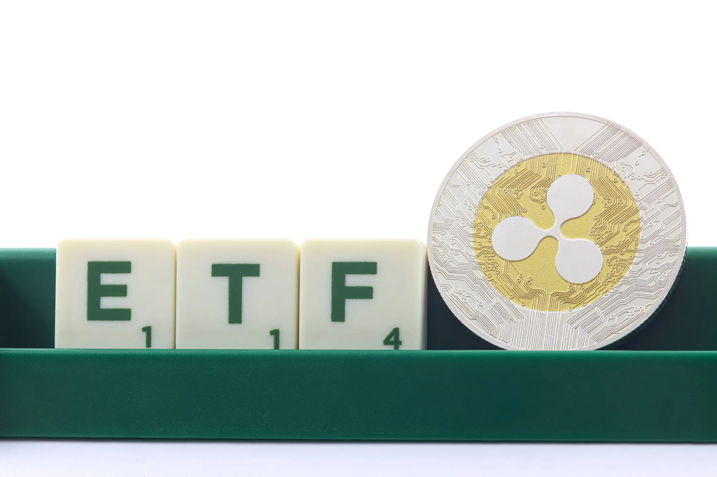 Ripple coin next to letter tiles spelling ETF, representing an XRP exchange-traded fund and crypto investment concept.