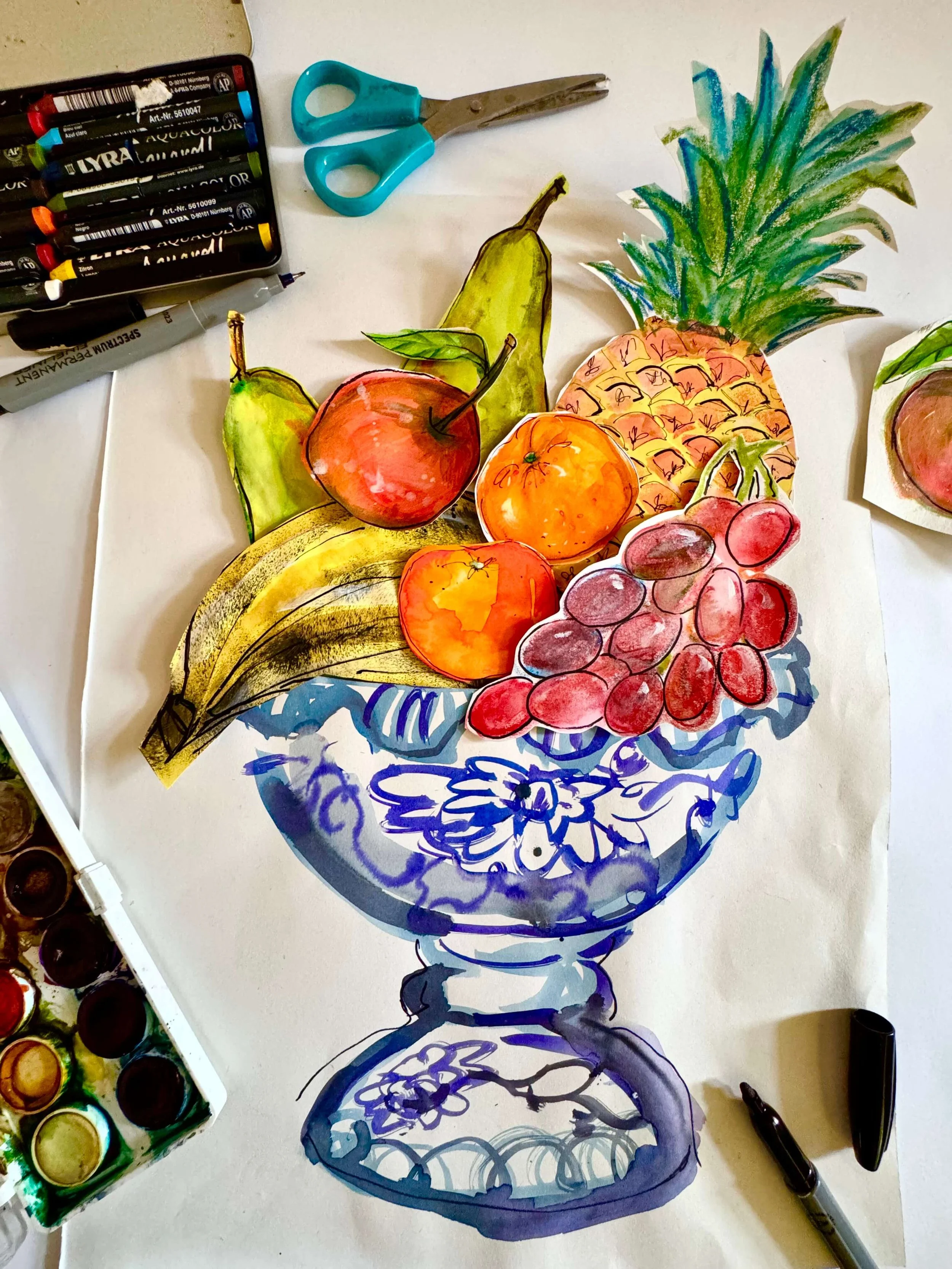 A desk with drawings of fruit cut out and placed in the position of a fruit bowl