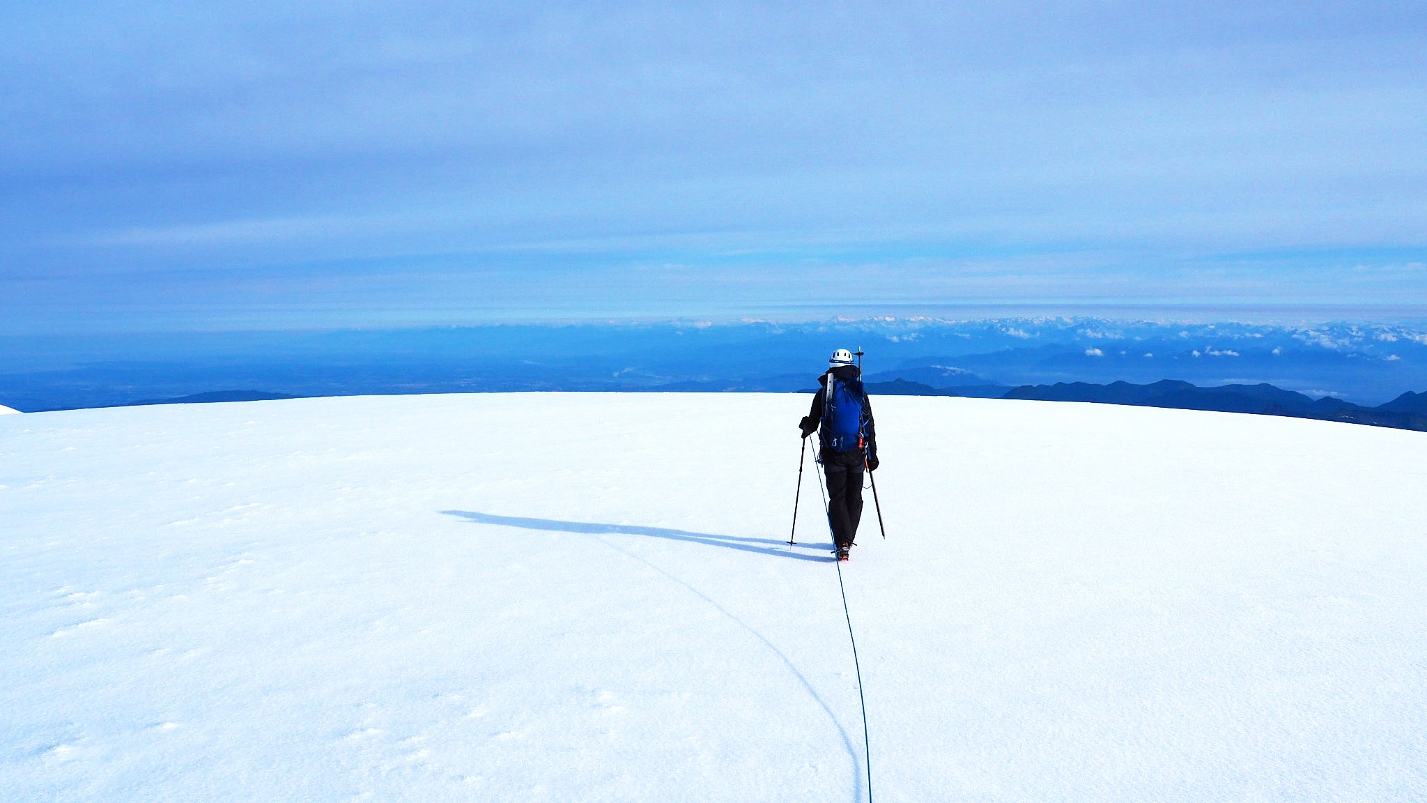 Roped-up mountaineer walking on large snowy surface