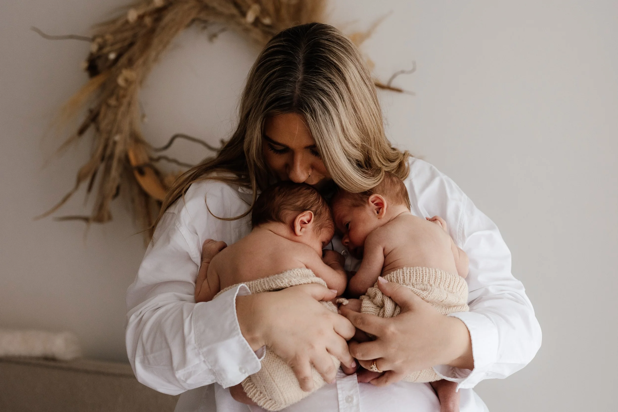 Mother holding newborn twins during a relaxed newborn photography session in the Scottish Borders
