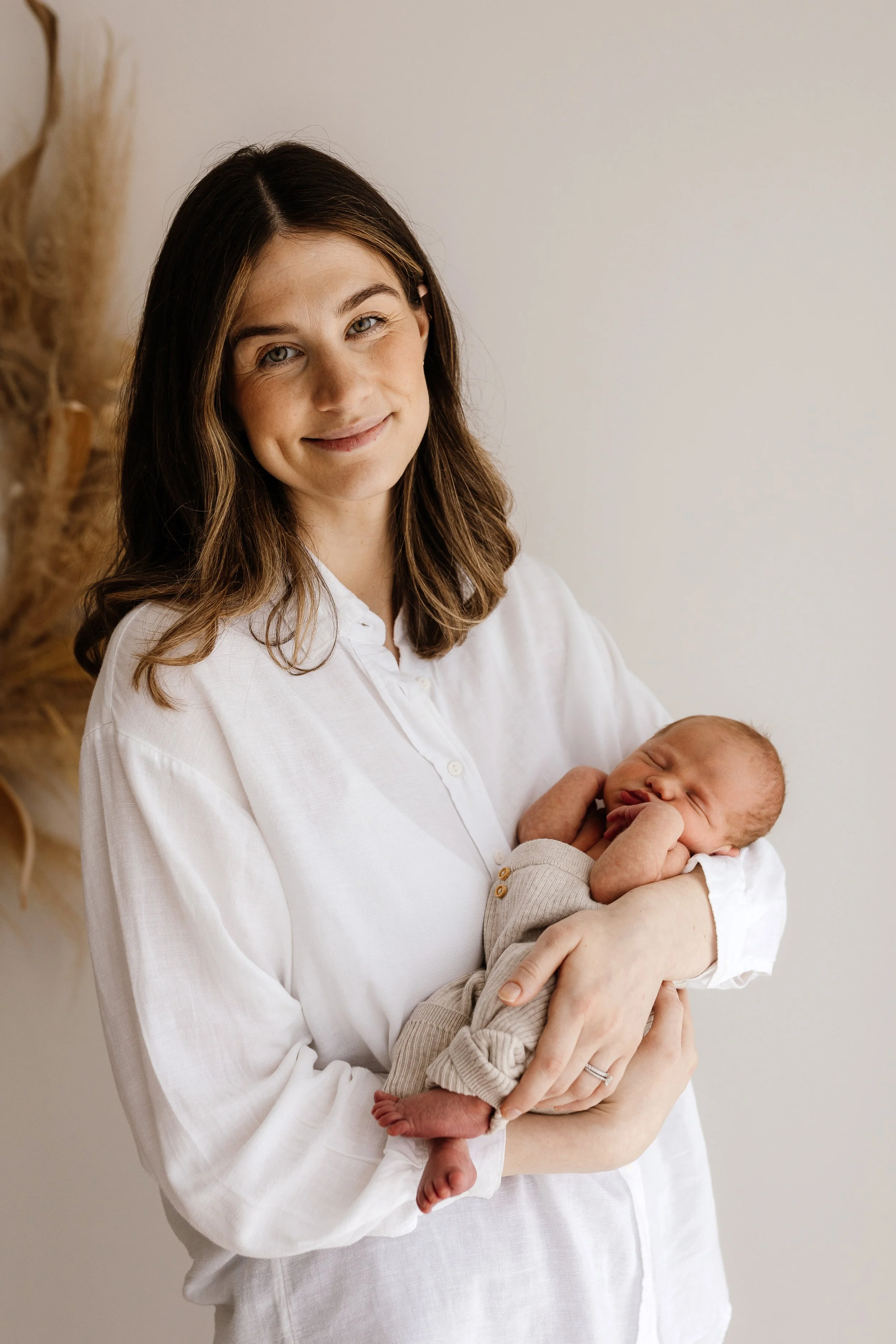 Mother holding her newborn baby in a simple white shirt during a relaxed newborn photography session