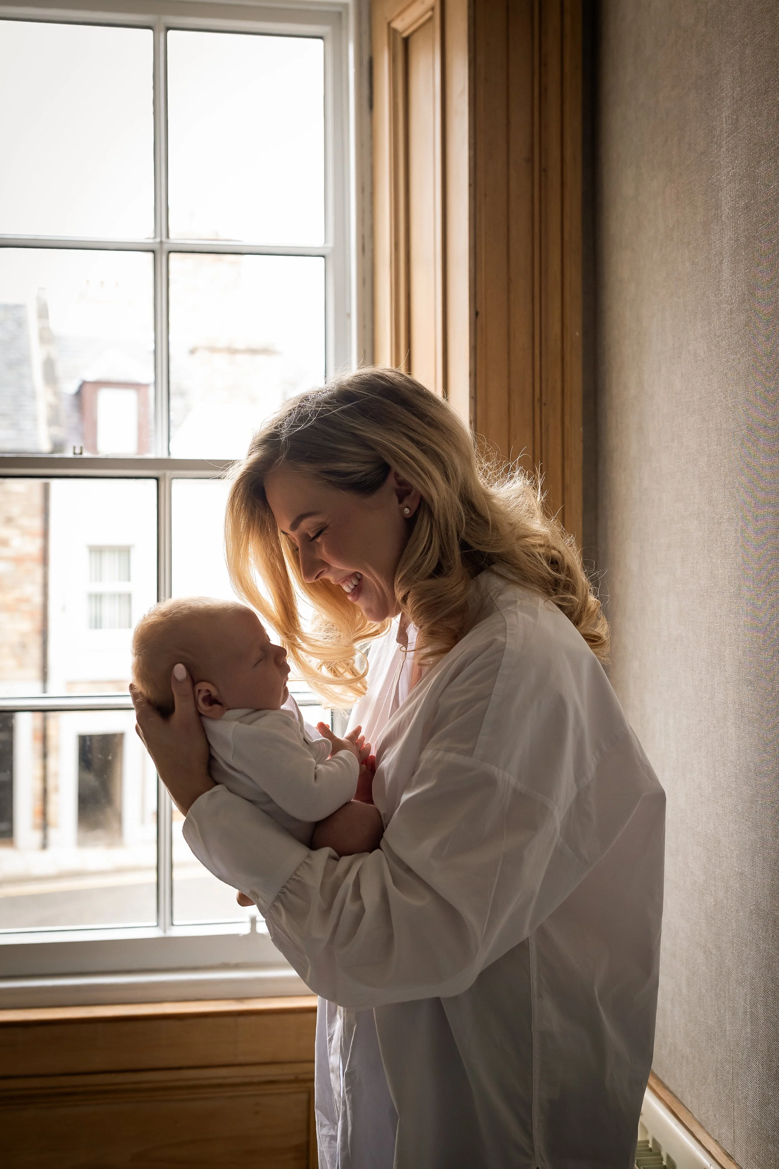new mother holding baby at the window, enamay photography
