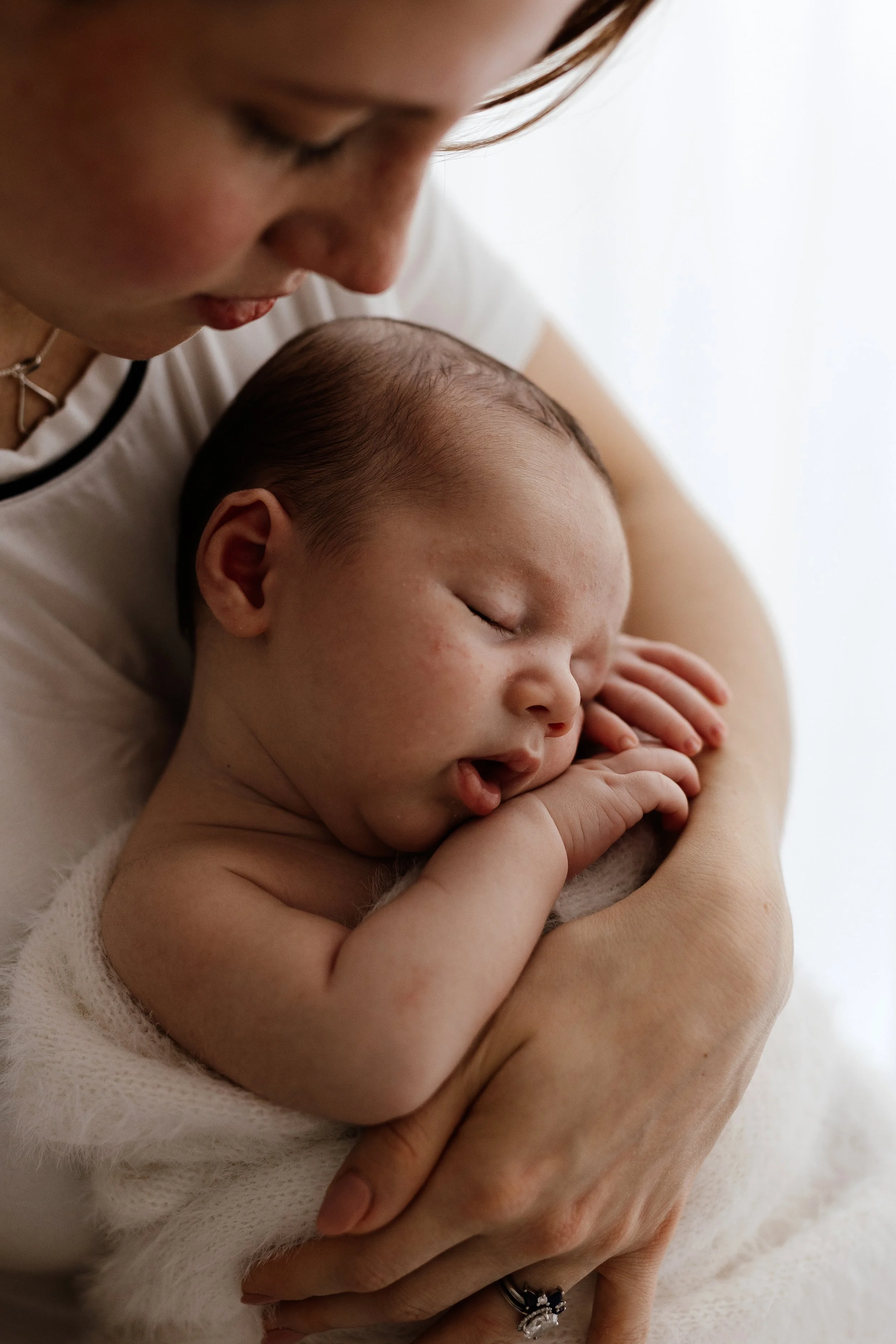 Close up photograph of mother cuddling her sleeping newborn baby during a calm studio newborn session