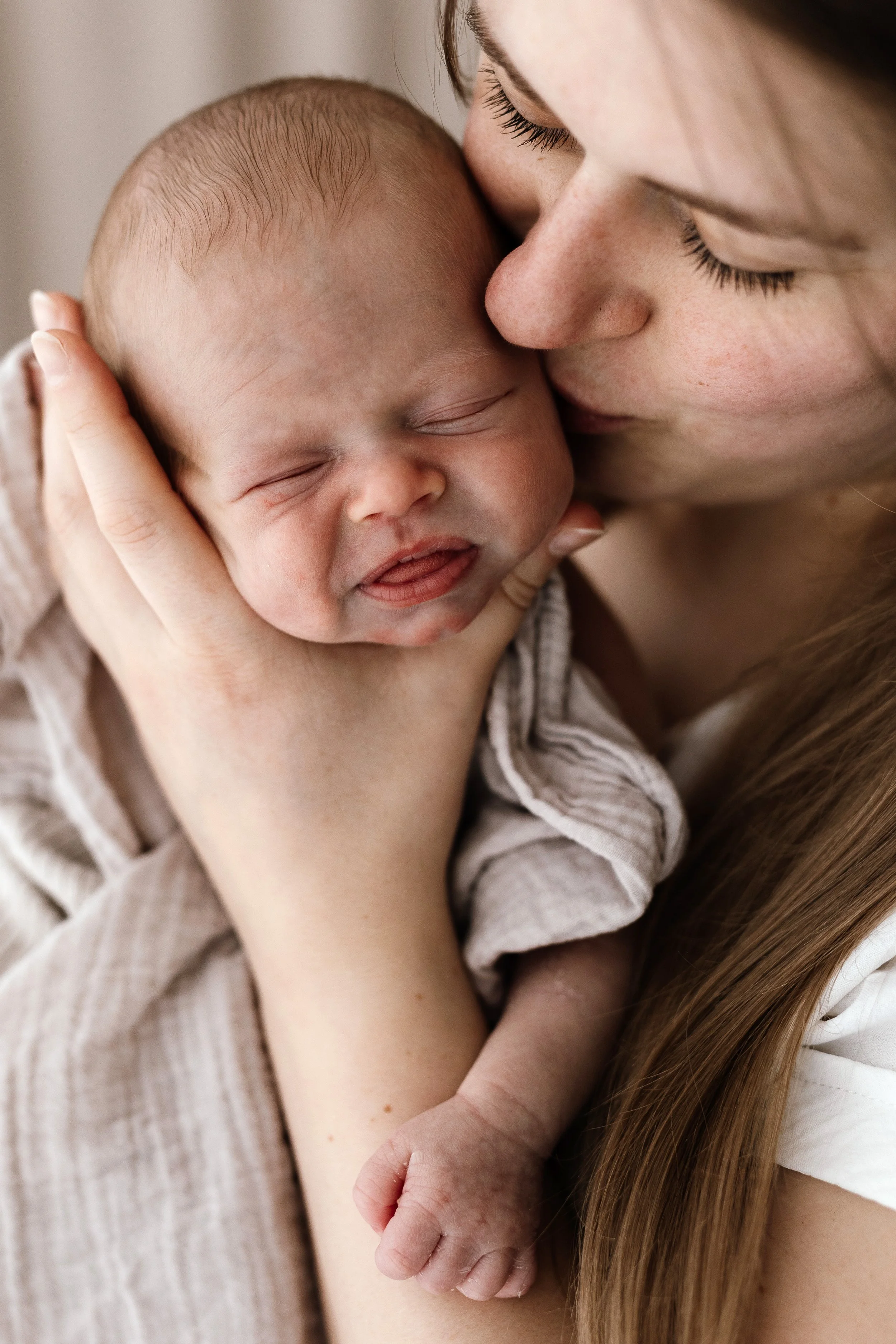 Close up of mother holding her newborn baby against her cheek during a gentle newborn photoshoot