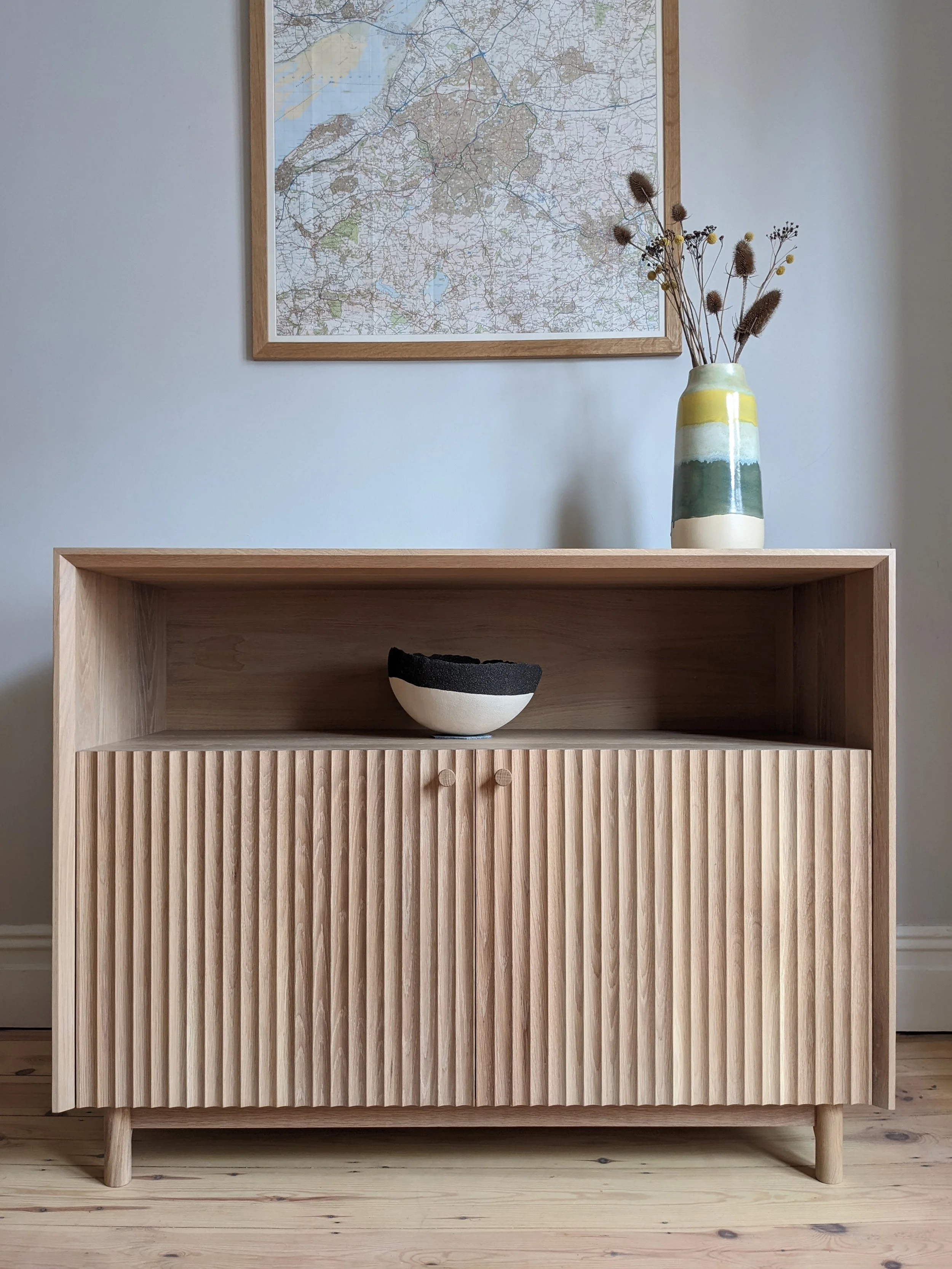 Sideboard in solid oak.
Mitred corners, fluted doors and internal adjustable shelves. Finished in a white-tinted hardwax oil to bring out the grain and protect the wood, but at the same time preserve the oak's raw natural appearance.