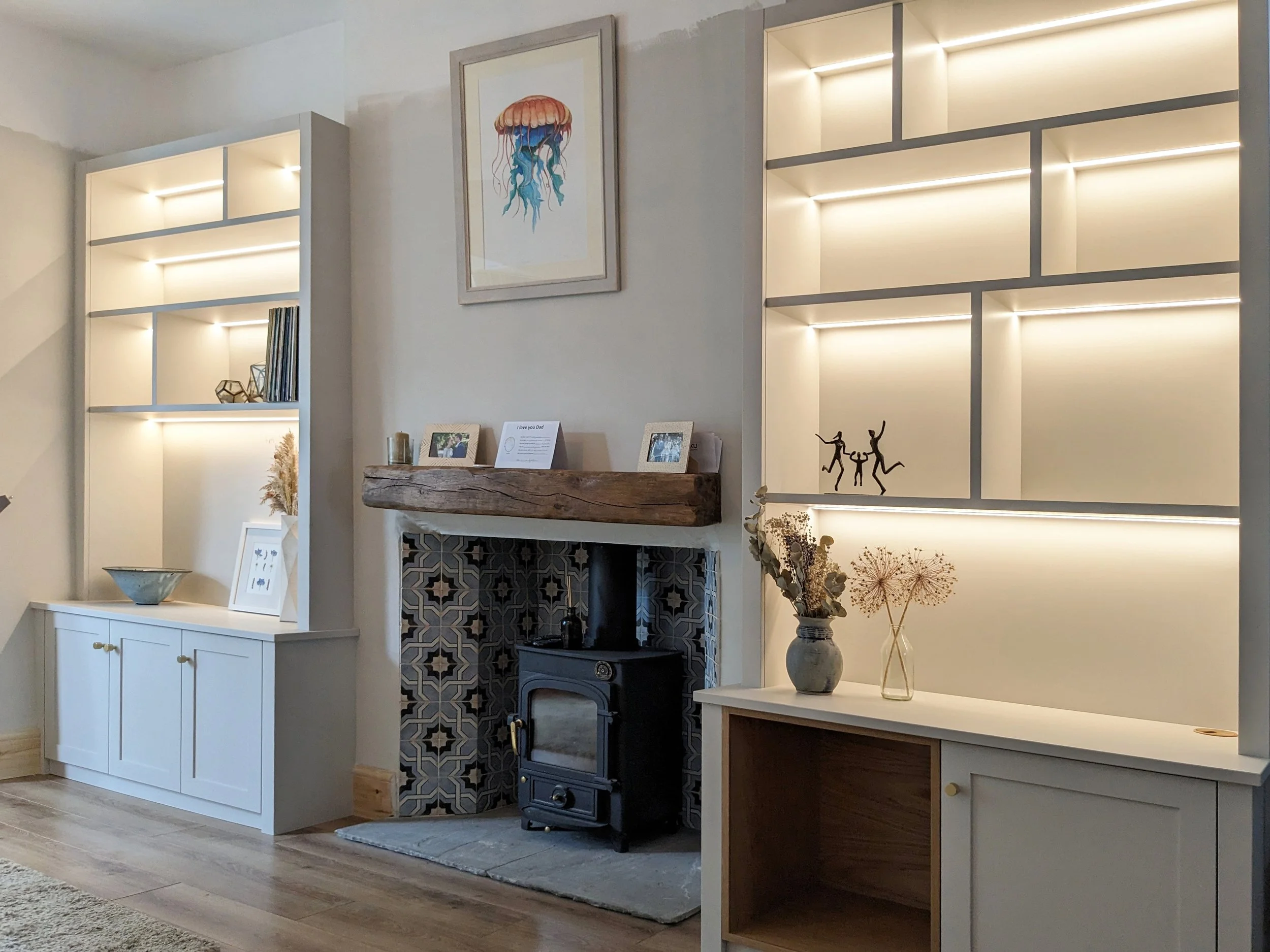 Traditional Shaker-style alcove units, with contemporary asymmetric shelving above.
Oak veneered cupboard internals and a log store lipped in solid oak, is finished off with a hand-painted exterior, colour-matched to the walls. LED backlighting usin