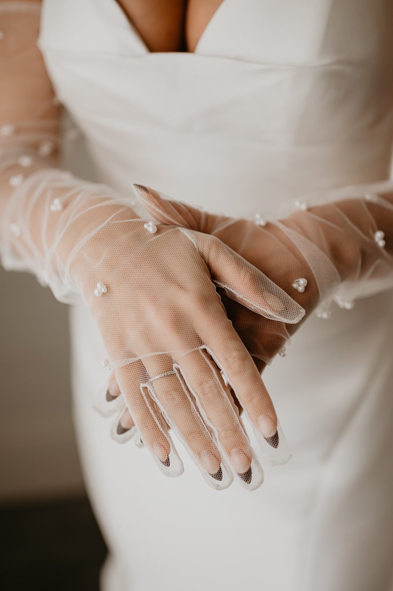 This detail photo captured by Julia Brown Photo, features the bride at Crimson Lane with a sweetheart neckline twirl dress, and stunning beaded gloves. 