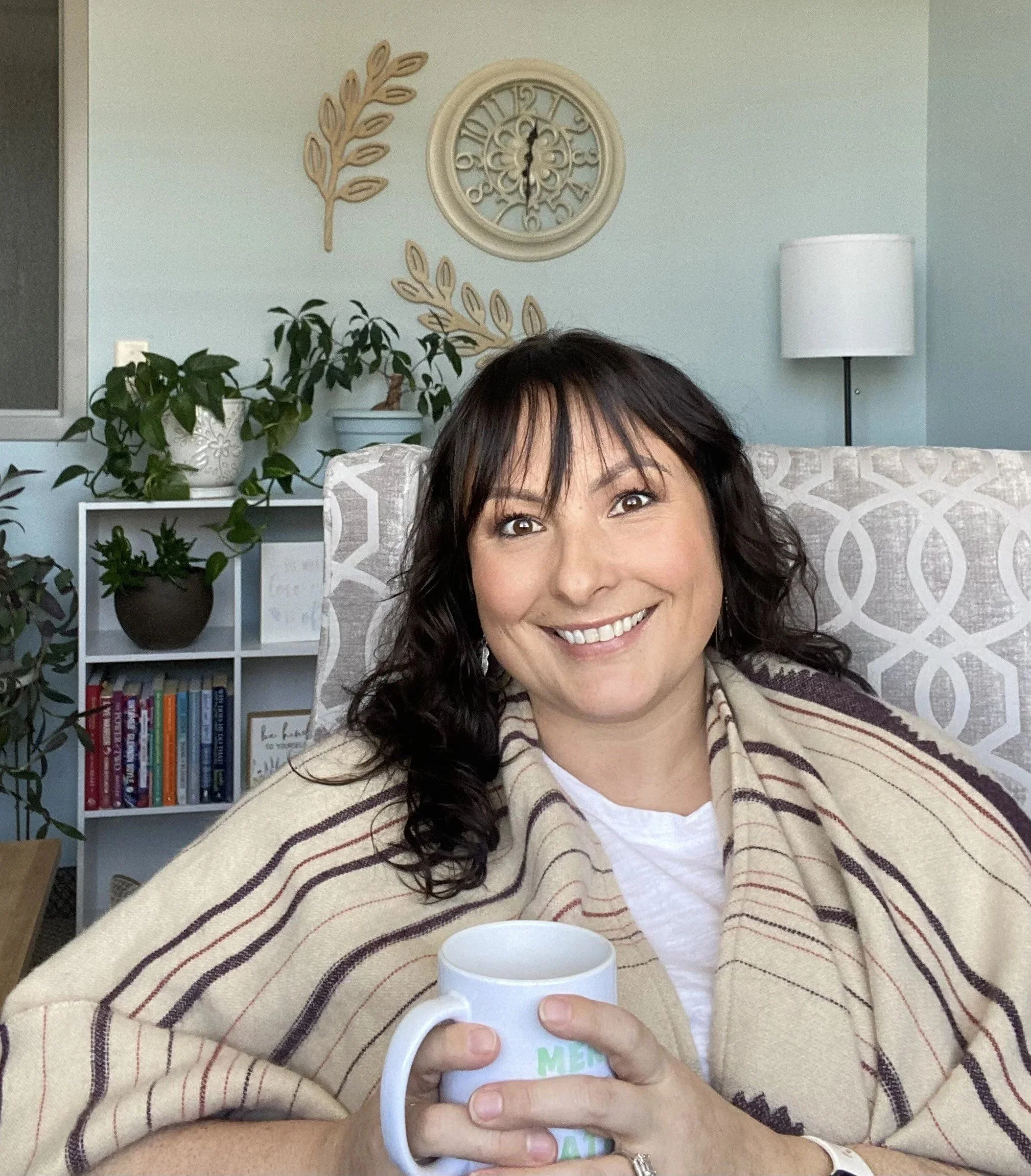 Counselor sitting in an office holding a cup of coffee.