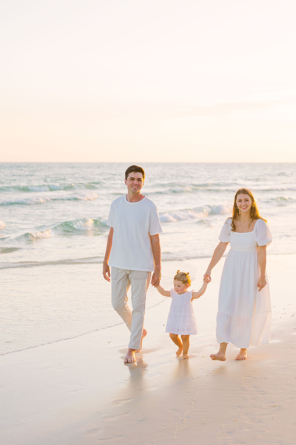 Couple and toddler walking along the beach.