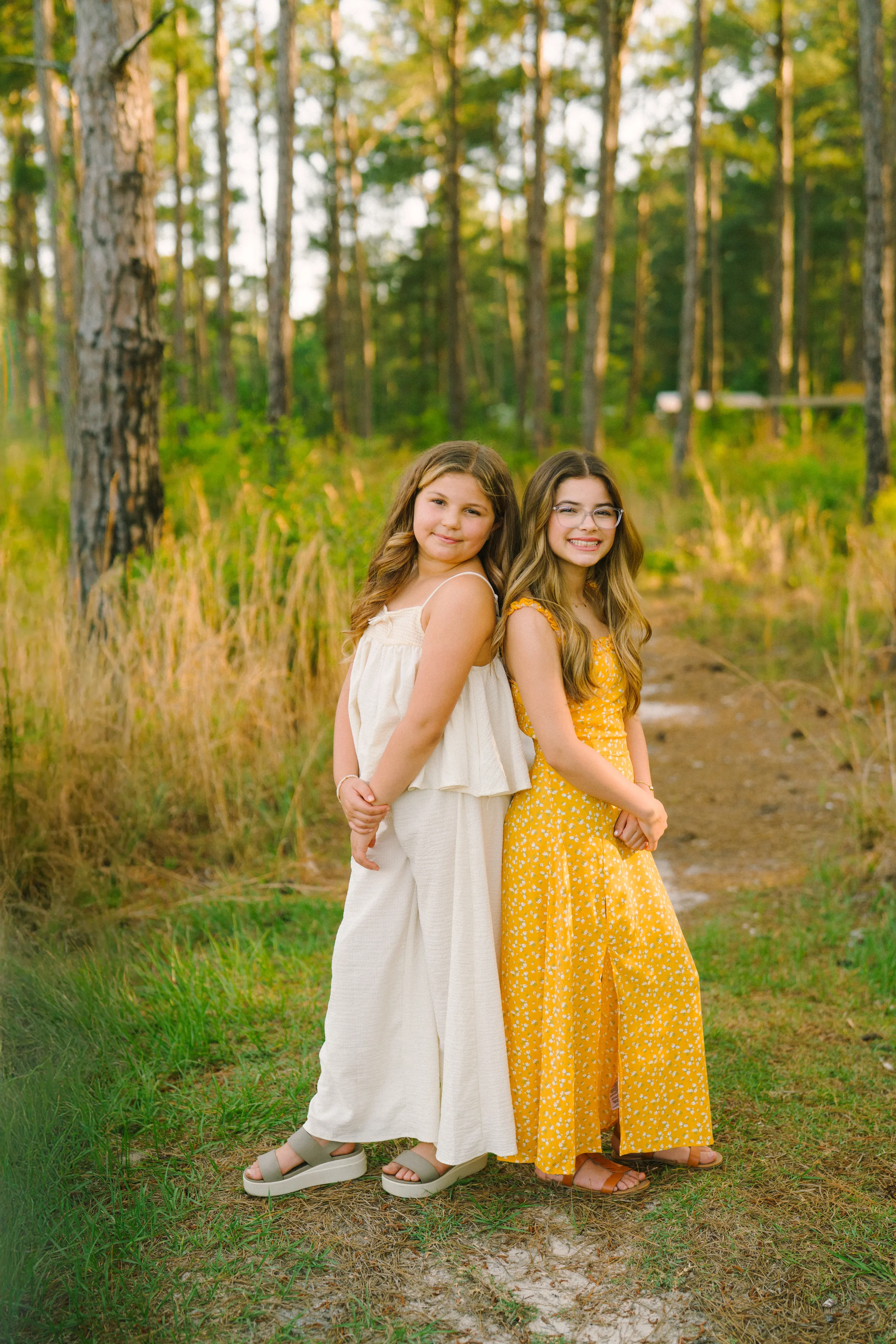 Freeport family photographer capturing two sisters in matching dresses outdoors