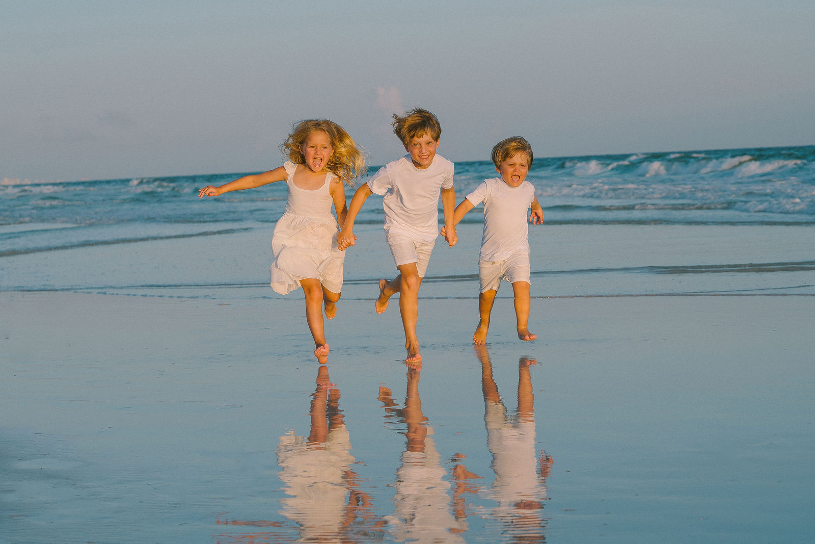 Three children running along the shoreline.