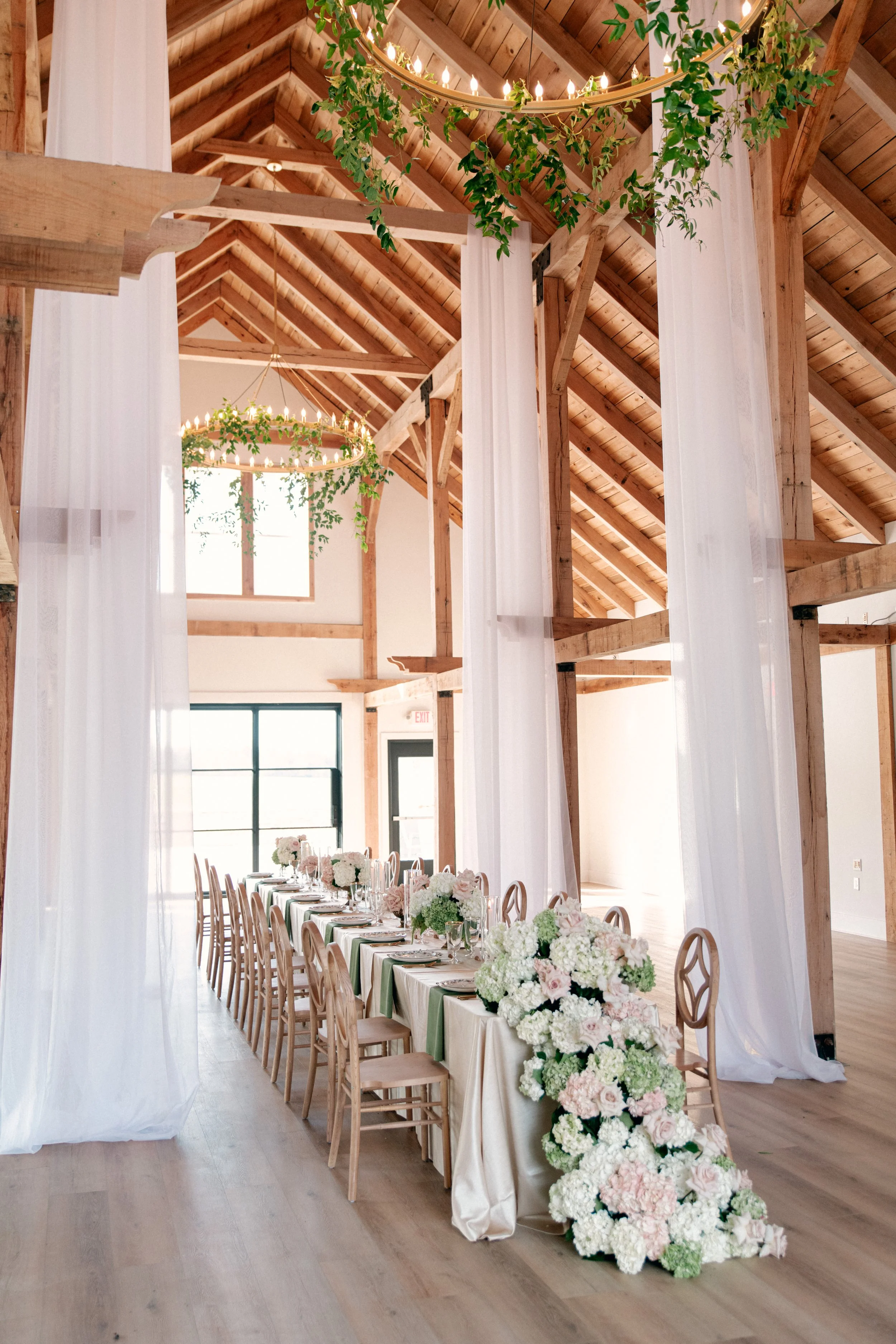 Reception design inside Cedar Hall at Jubilee Woods with long tables and floral centerpieces
