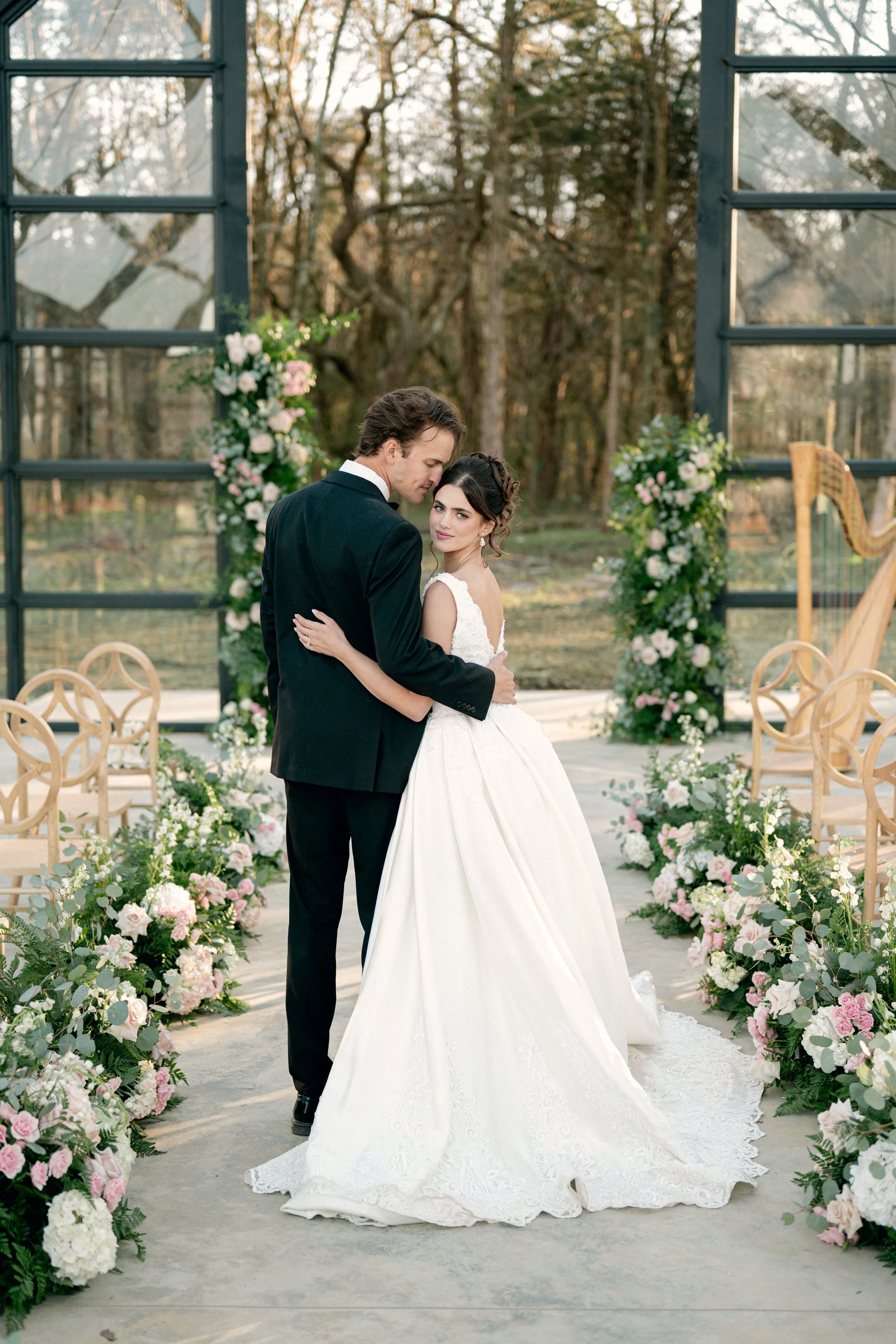 a bride and groom posed elegantly inside of the glass chapel at Jubilee Woods in middle Tennessee, a new wedding venue in the area surrounding Nashville.
