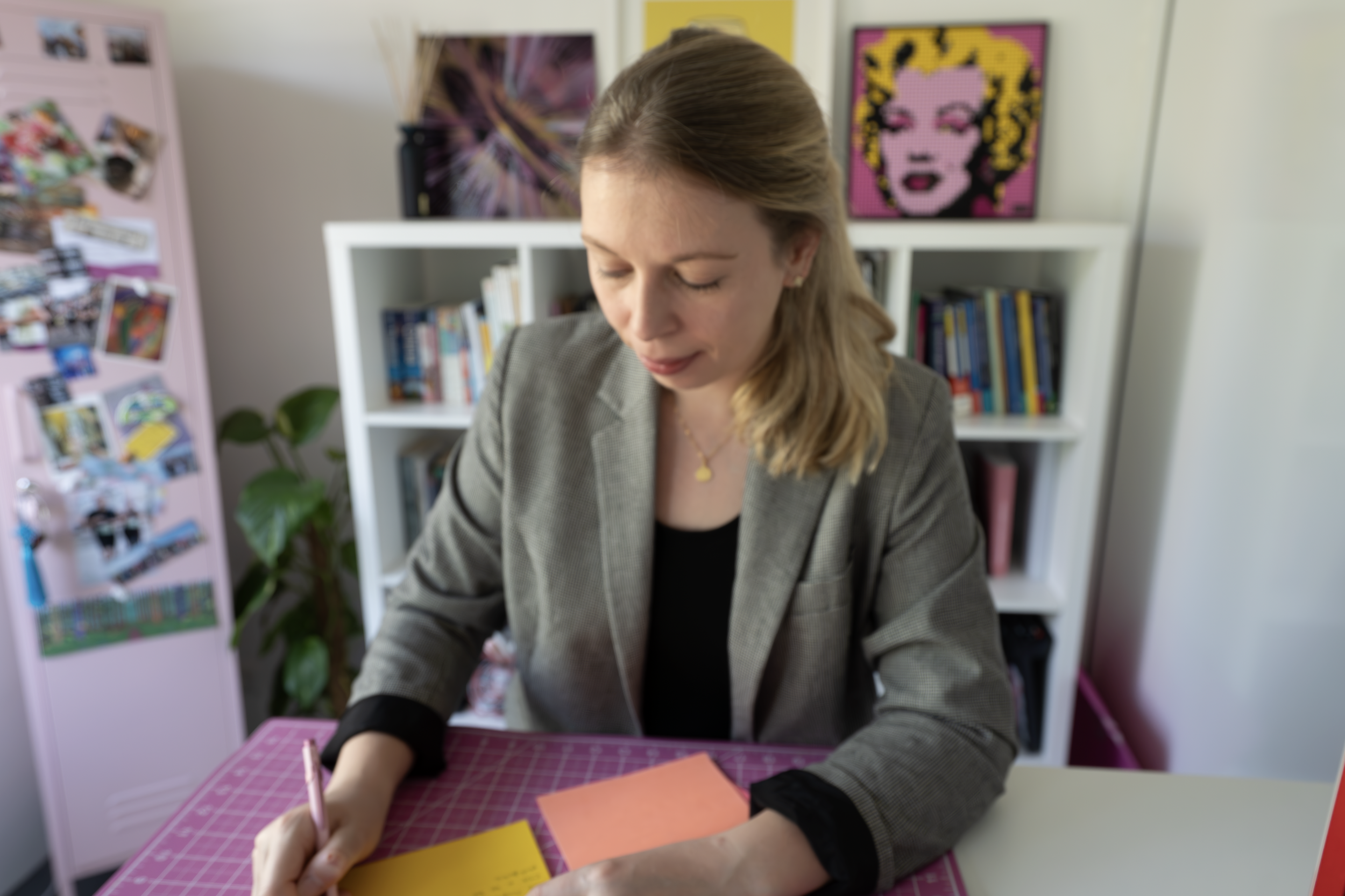 Podcast and Video Producer, Laura Wilkes, standing at a desk making notes while planning a podcast episode.