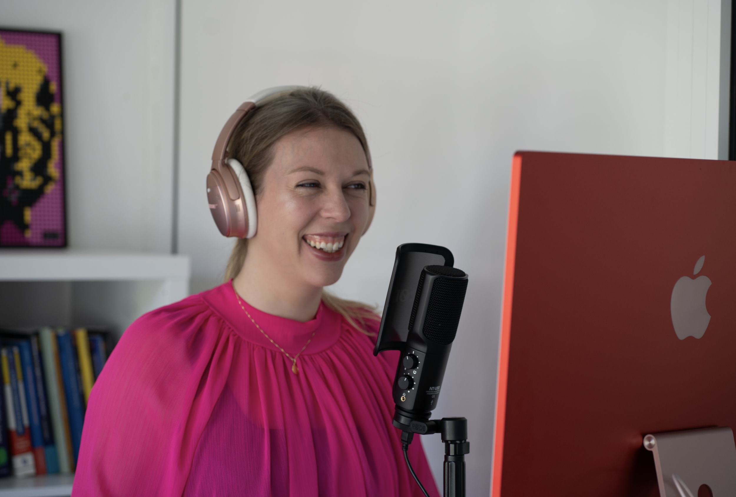 Podcast and Video Producer, Laura Wilkes, standing in front of a microphone wearing headphone while recording a show.