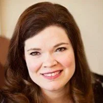 Headshot of a woman with brown hair, smiling at the camera.