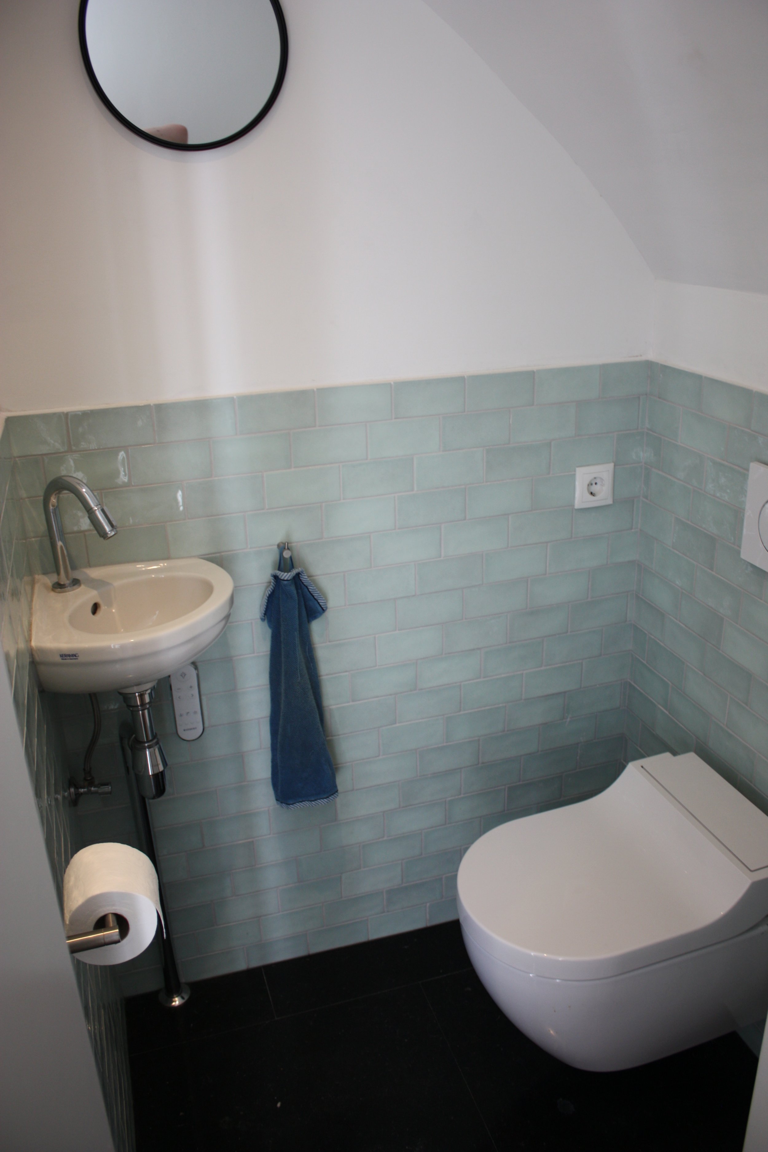 Toilet renovatie met hardstenen vloer gelegd met minimale voeg, met rond gestuct plafond onder trap. Toilet voorzien van Geberit Aquaclean Bidet.