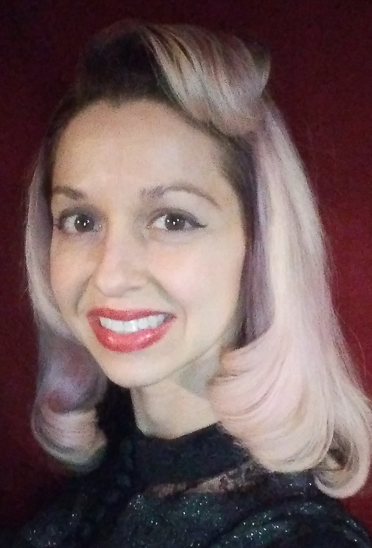 A woman with blonde hair styled in soft waves, wearing red lipstick, dark eyeshadow, and a black, shimmery top, smiling against a dark red background.