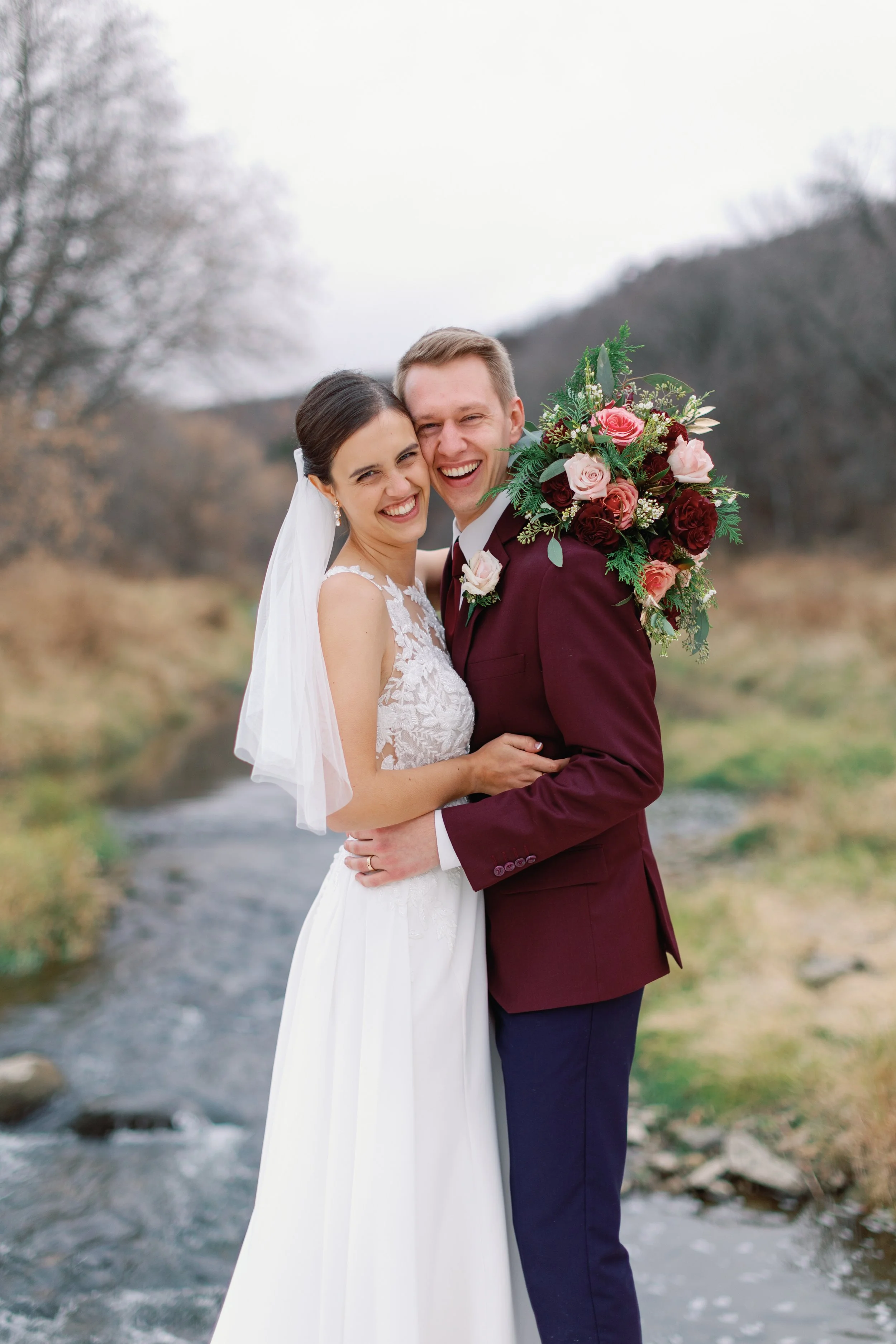 Carissa and Riley on their wedding day with a stream running behind them