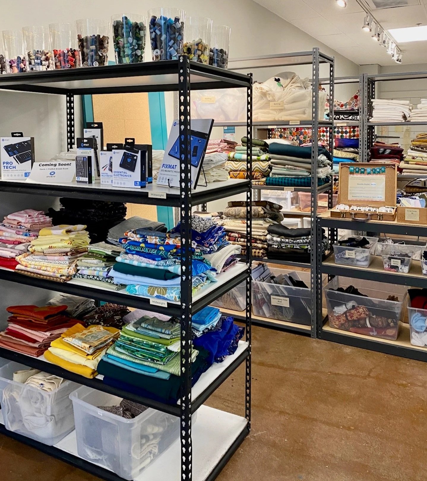 Shelves filled with folded fabrics, cloths, and sewing supplies in a craft or fabric store.
