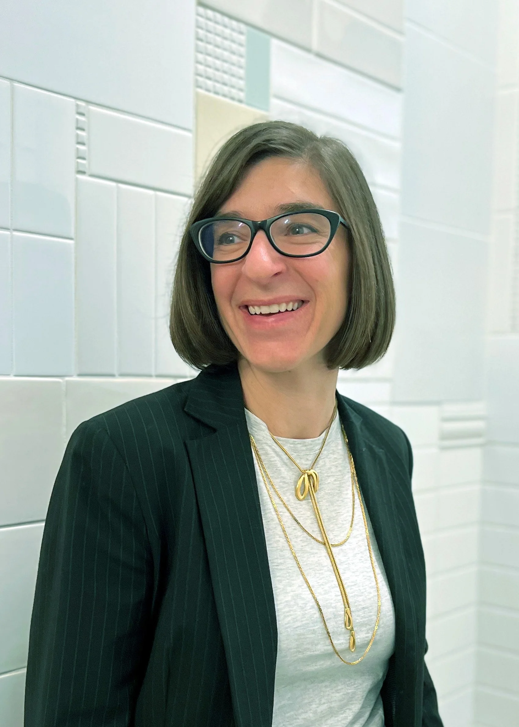 Image of a woman with short brown hair in front of a tile wall.