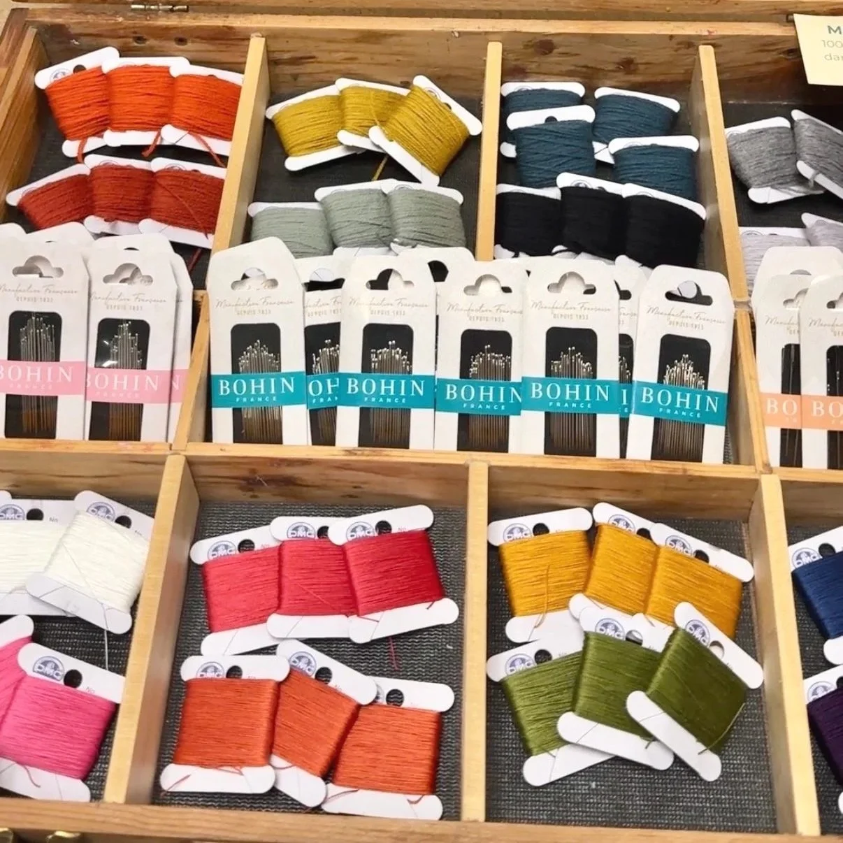 Packs of colorful threads laid out in a wooden tray