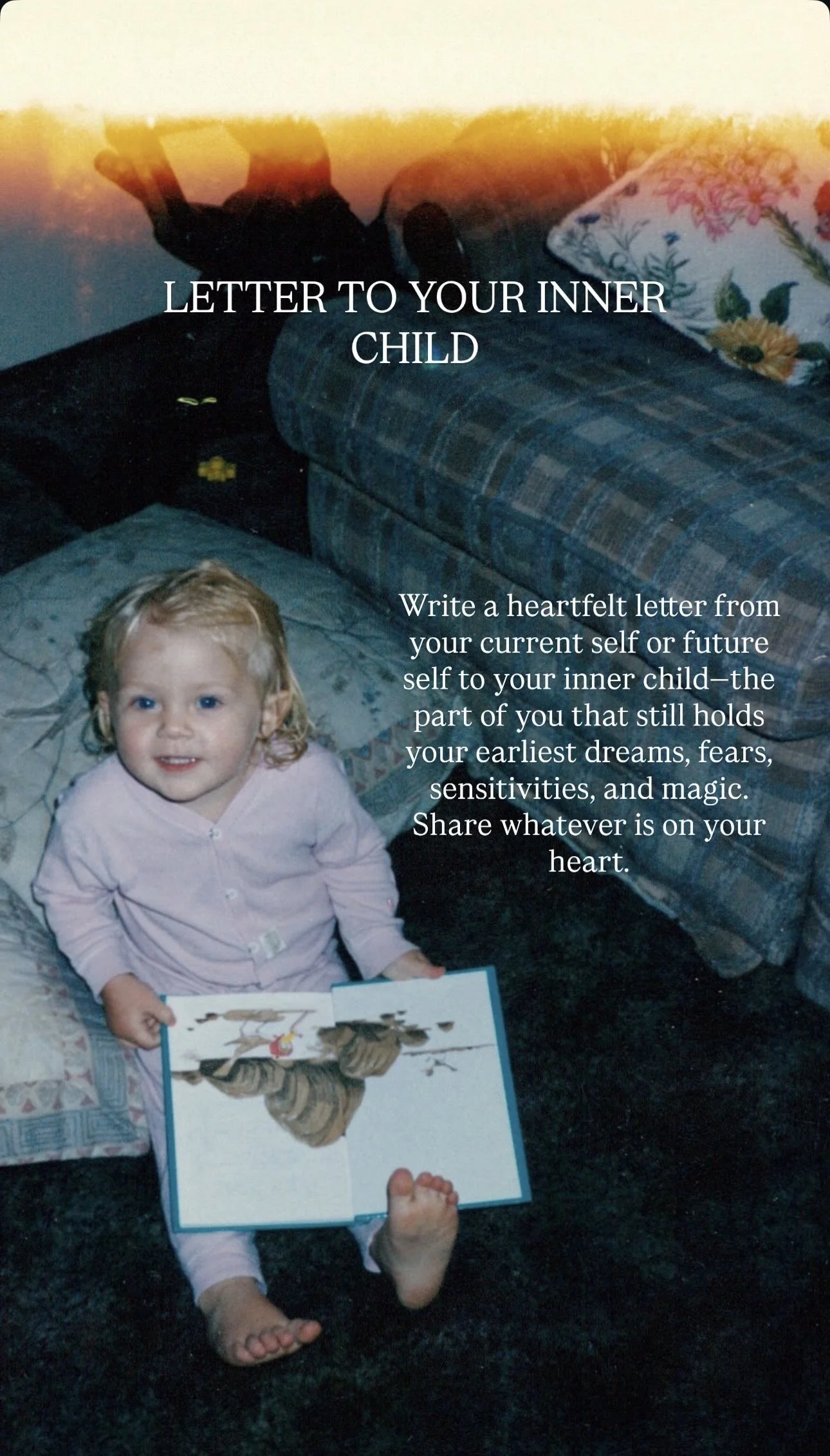 A young girl sitting on a dark carpeted floor, holding an open picture book with an illustration of a horse. She has blonde curly hair and is wearing a light pink pajama set. Behind her, there is a patterned couch and a floral pillow. The image has t