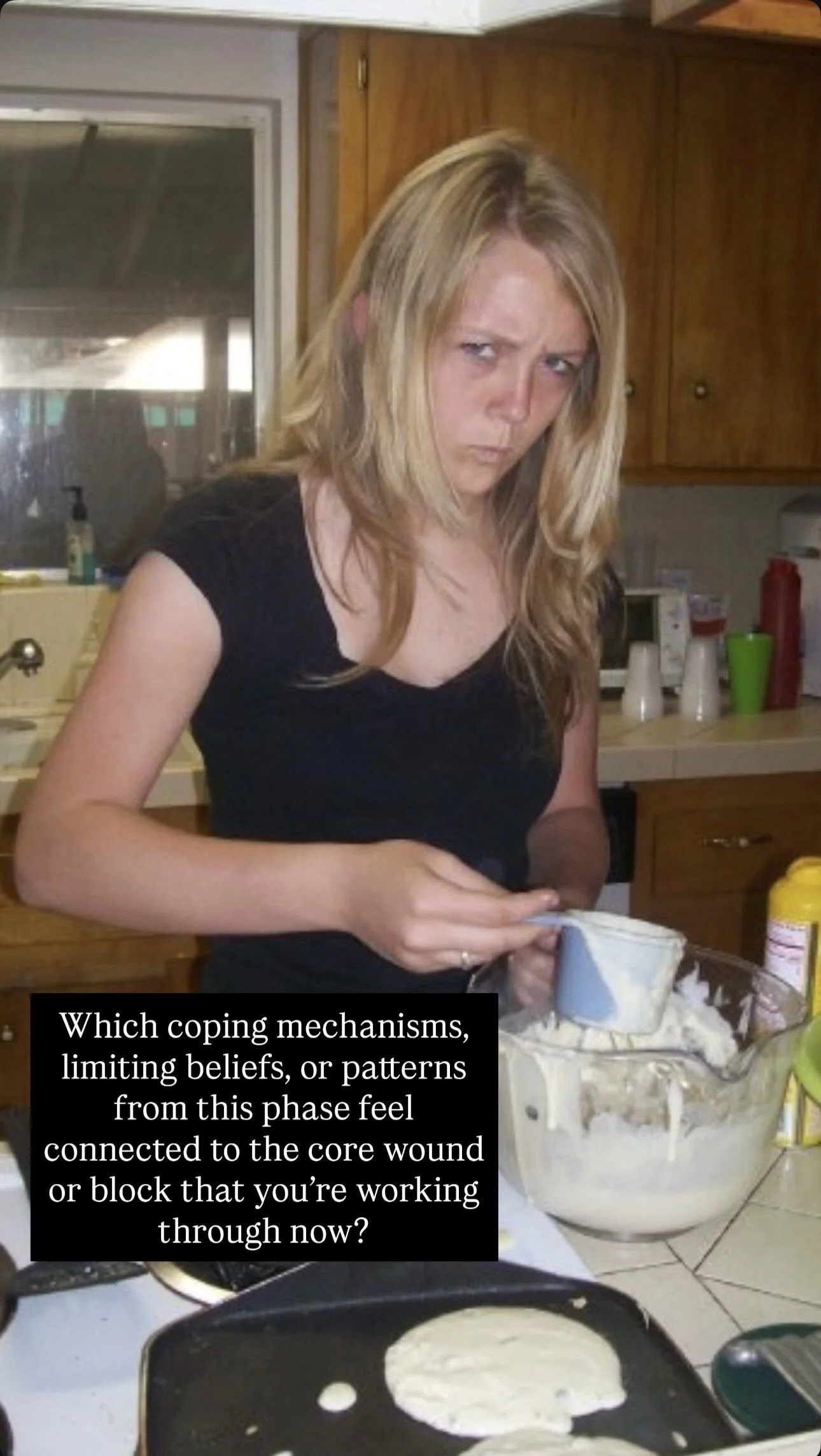 A woman in a black shirt baking in a kitchen filled with kitchenware and ingredients.