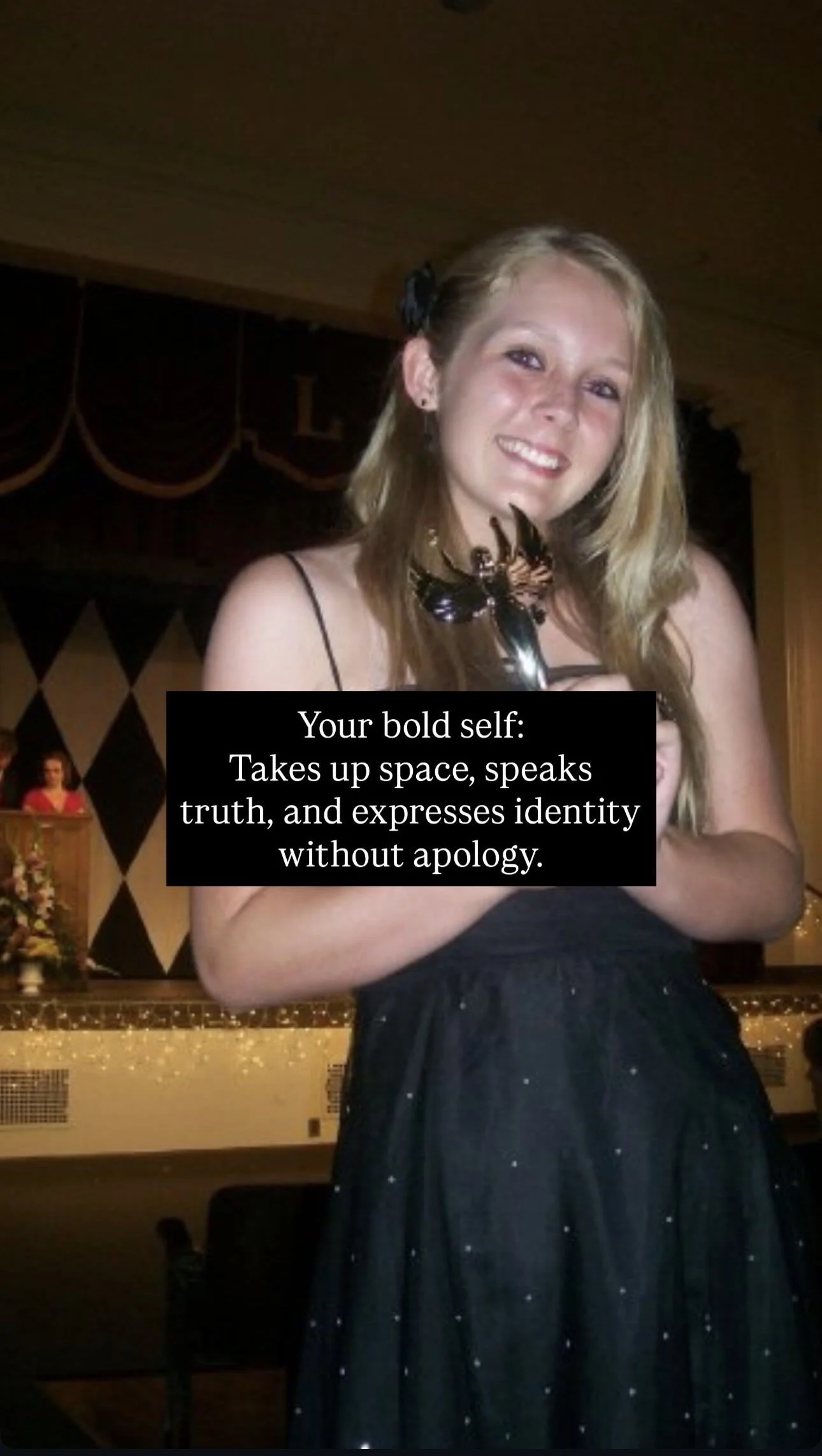 A young woman with blonde hair, wearing a black dress, holding an award, smiling at an event.